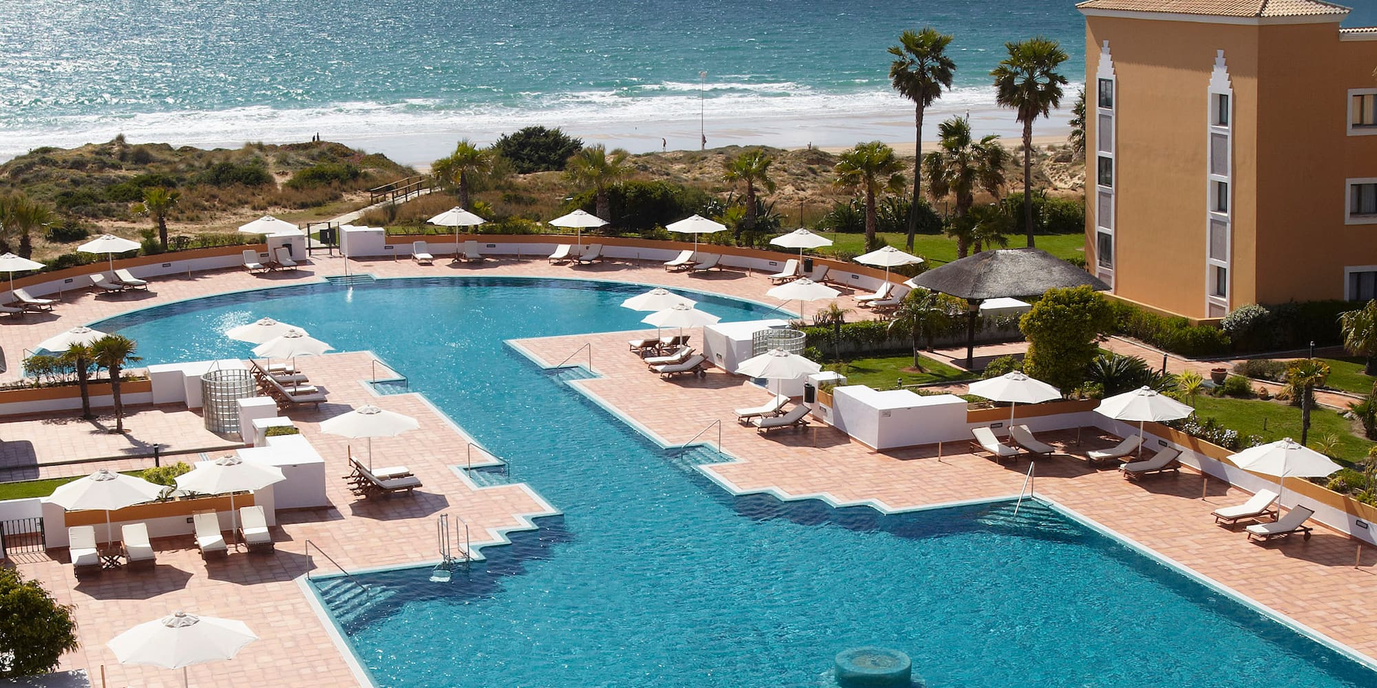 a swimming pool with umbrellas and chairs by a building