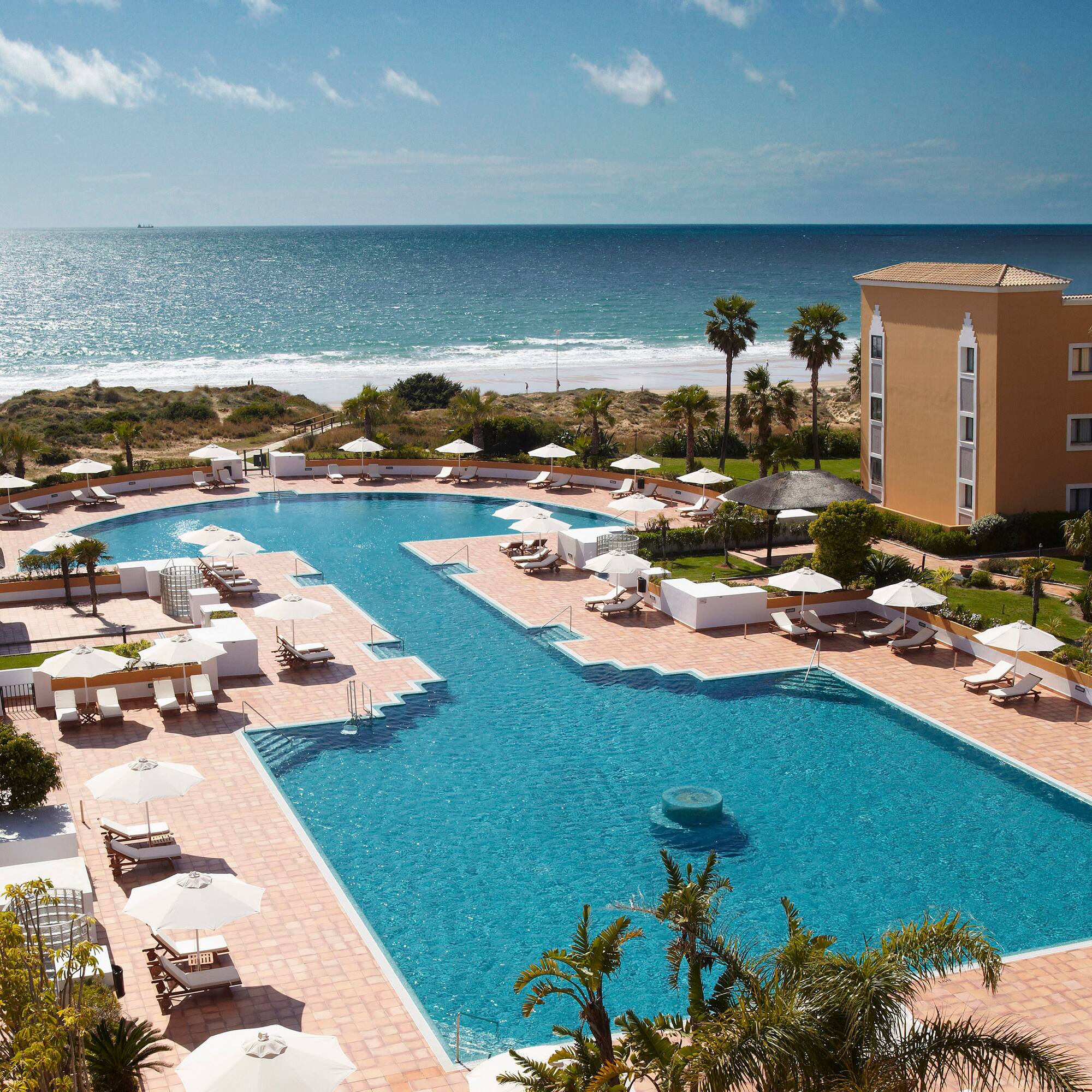 a swimming pool with umbrellas and chairs by a building