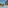 Hotel swimming pool with building, balconies, and thatched sun umbrellas.
