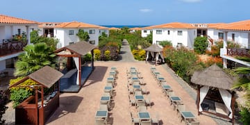 a group of tables and chairs in a courtyard with white buildings and blue sky