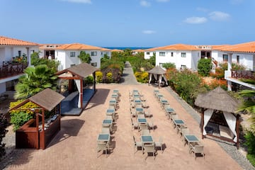 a group of tables and chairs in a courtyard with white buildings and blue sky