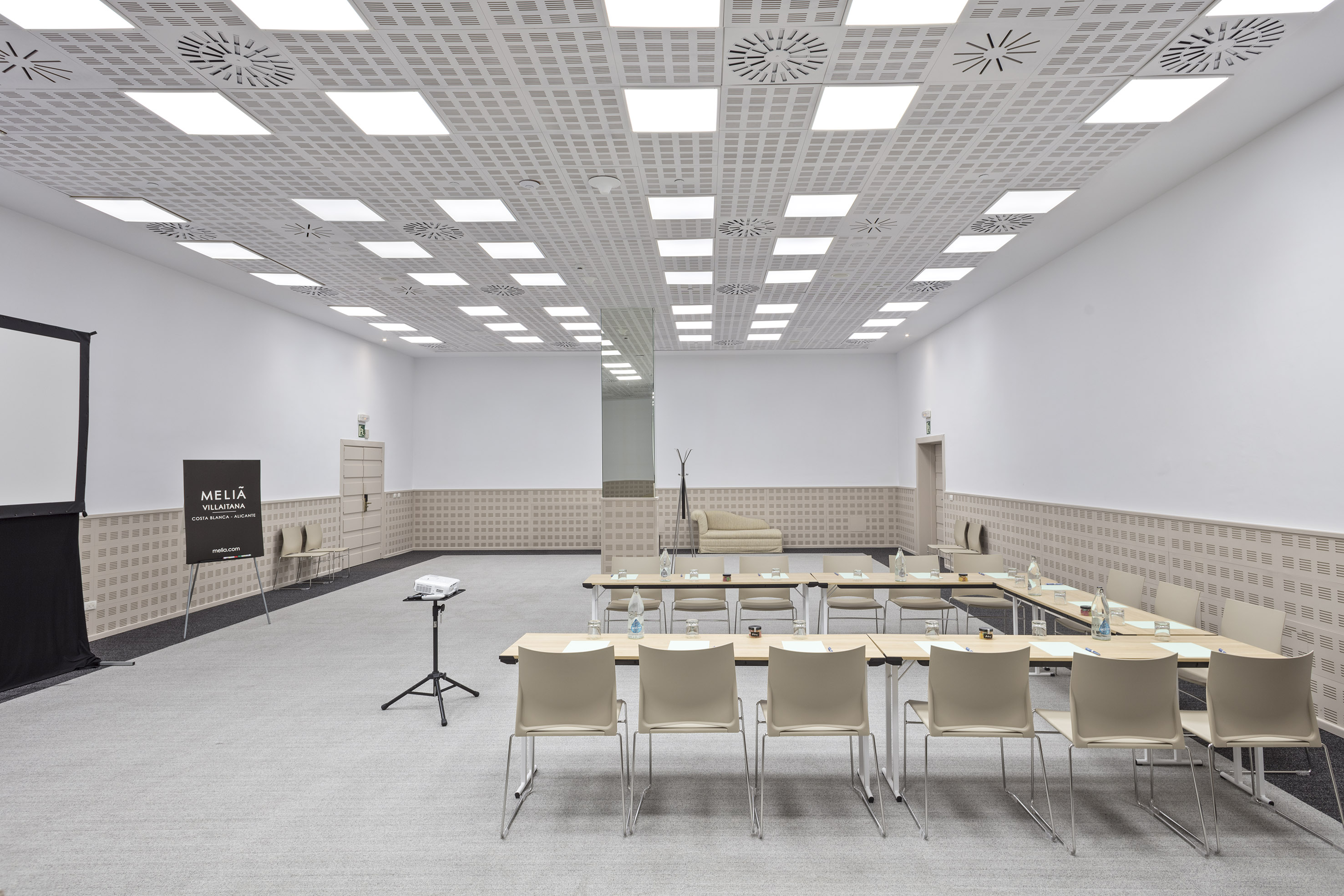 Bright modern conference room with U-shaped tables, projector, Meliá sign.