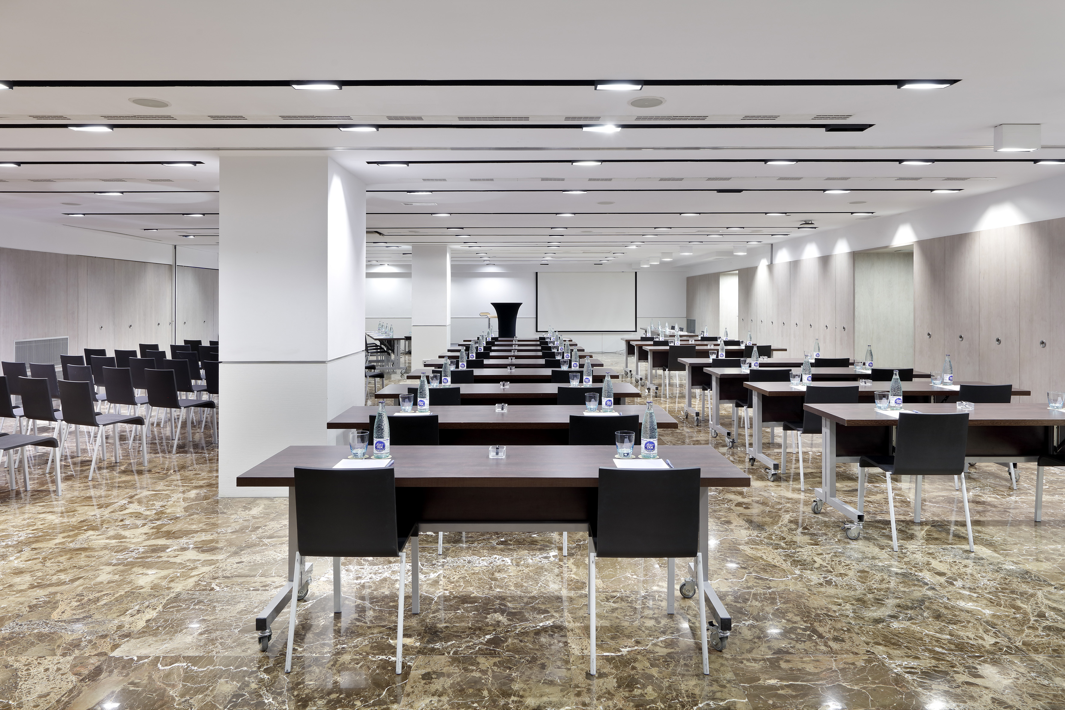 Modern conference room with tables, chairs, projection screen, and marble floor.