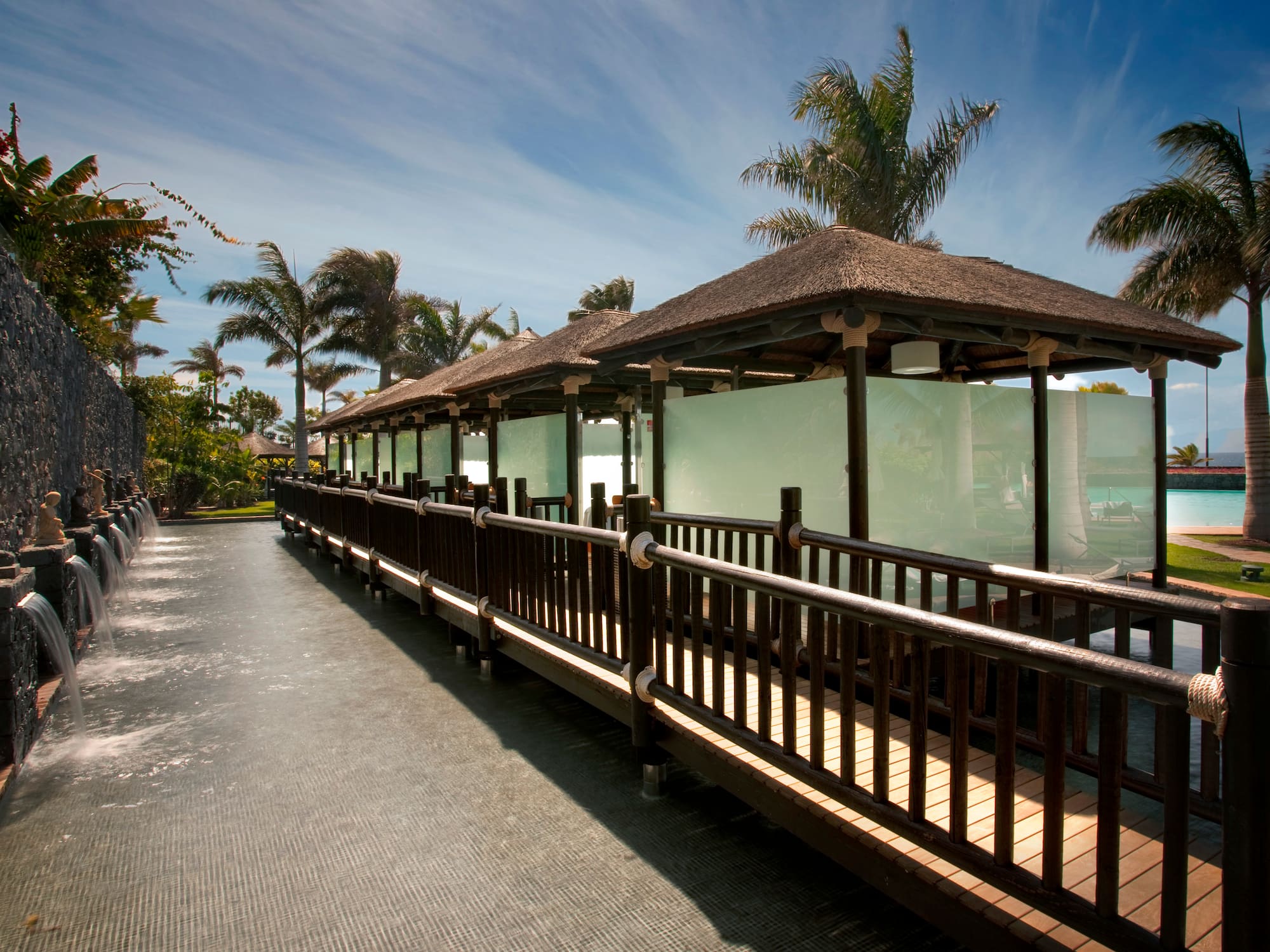 a walkway with a building and palm trees