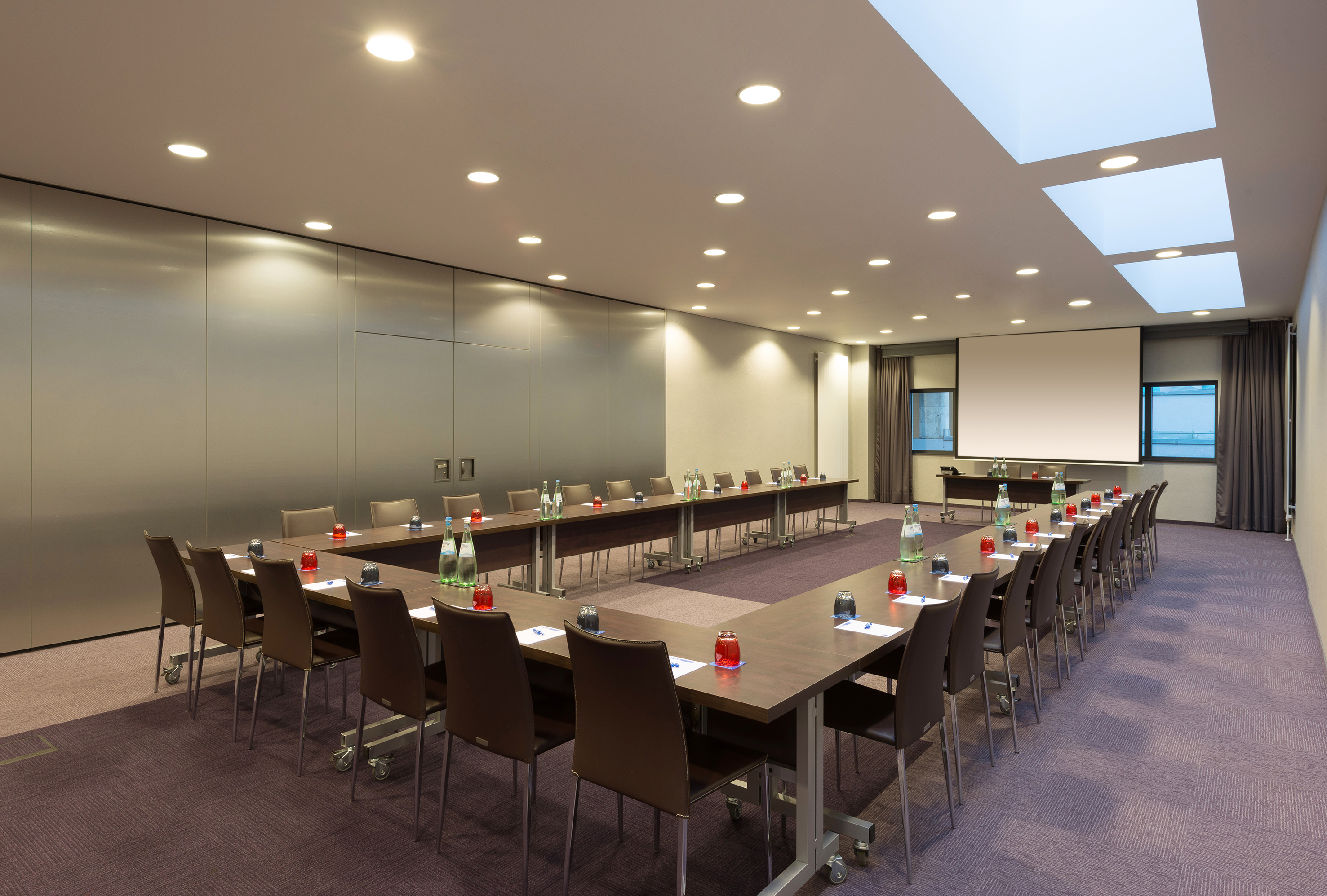Modern U-shaped conference room with projector screen and seating.
