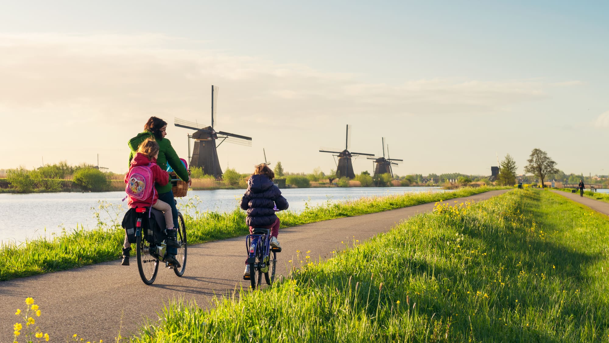 a group of people riding bikes on a path with windmills in the background