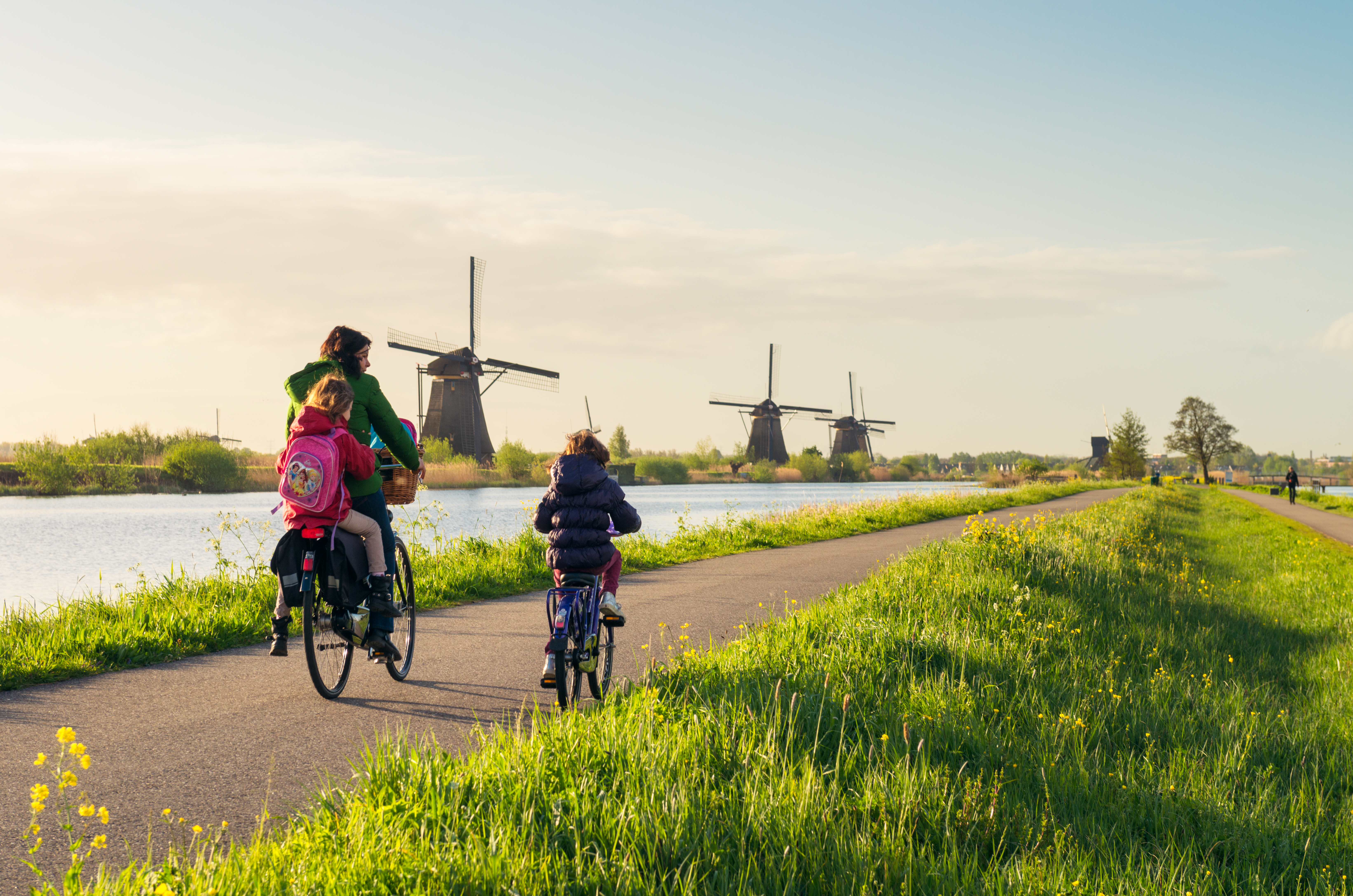 a group of people riding bikes on a path with windmills in the background