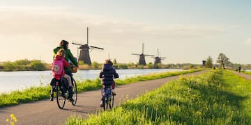 a group of people riding bikes on a path with windmills in the background