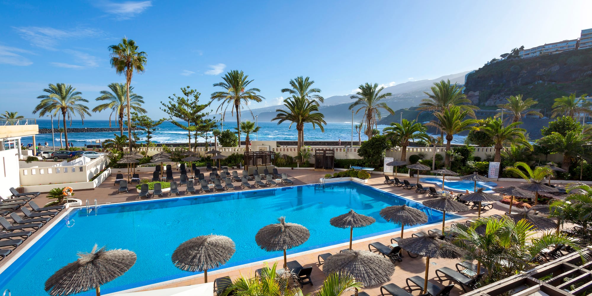 a pool with umbrellas and chairs and palm trees
