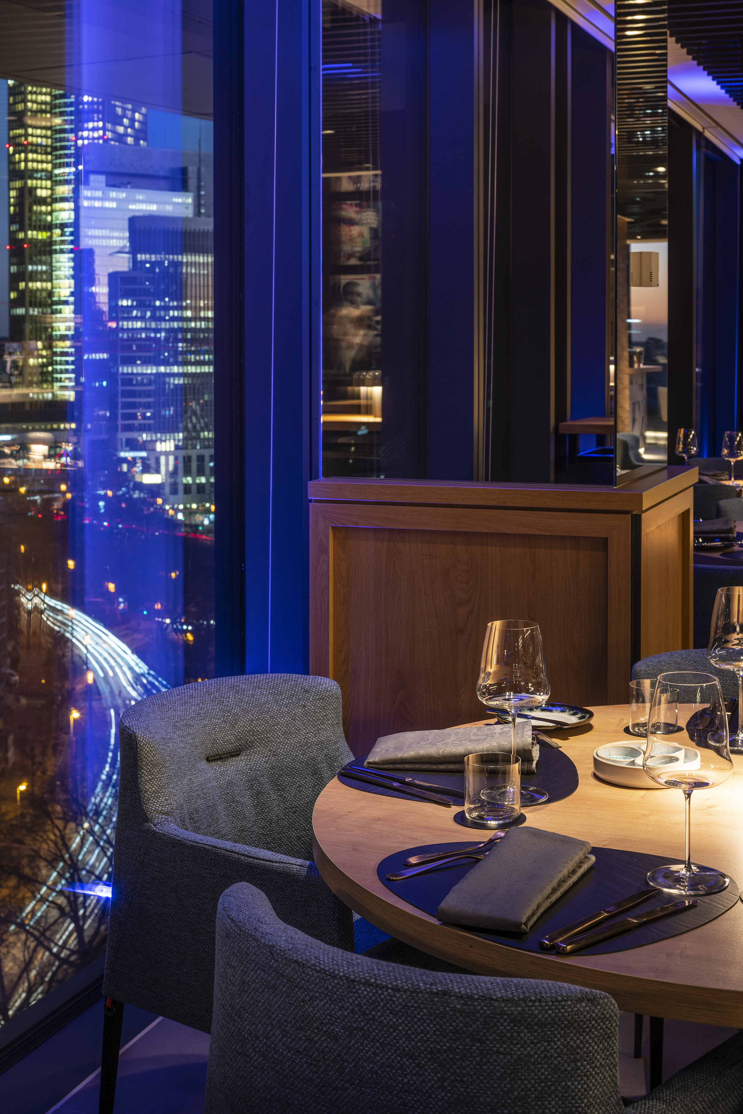 Upscale restaurant table setting with city skyline view at night.
