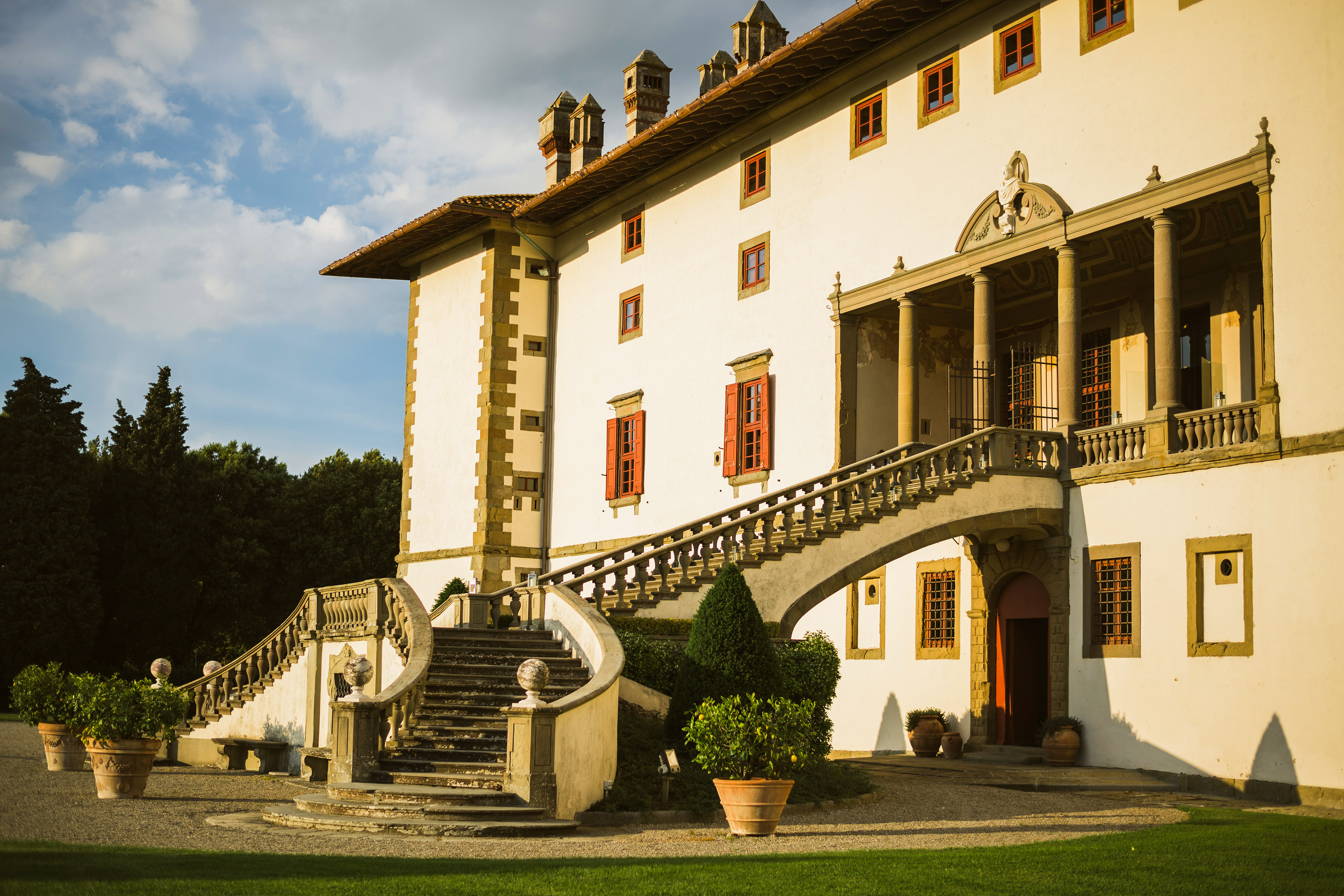 a large white building with a staircase and a green lawn