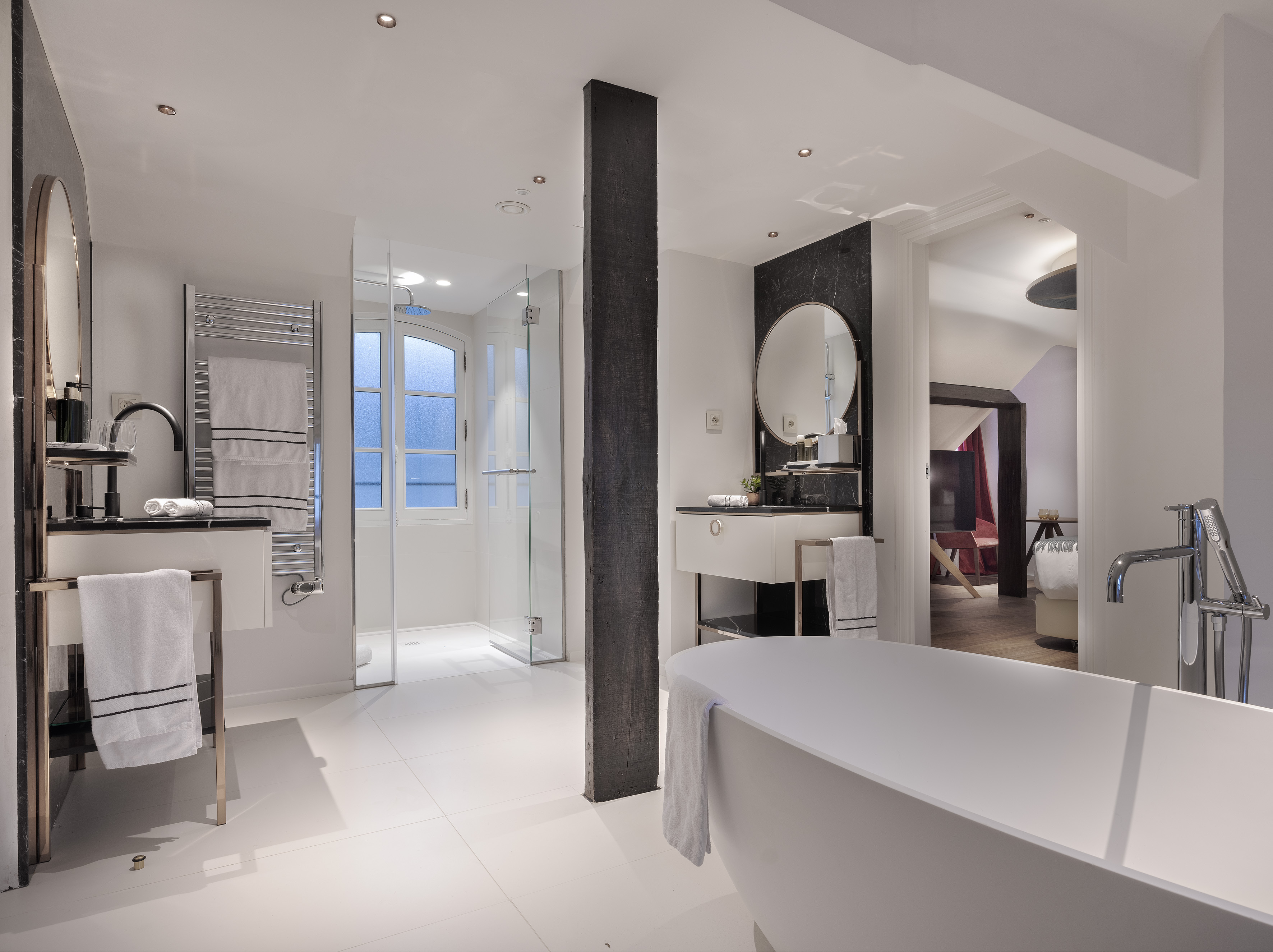 Modern luxury bathroom with freestanding tub, double vanity, and glass shower.