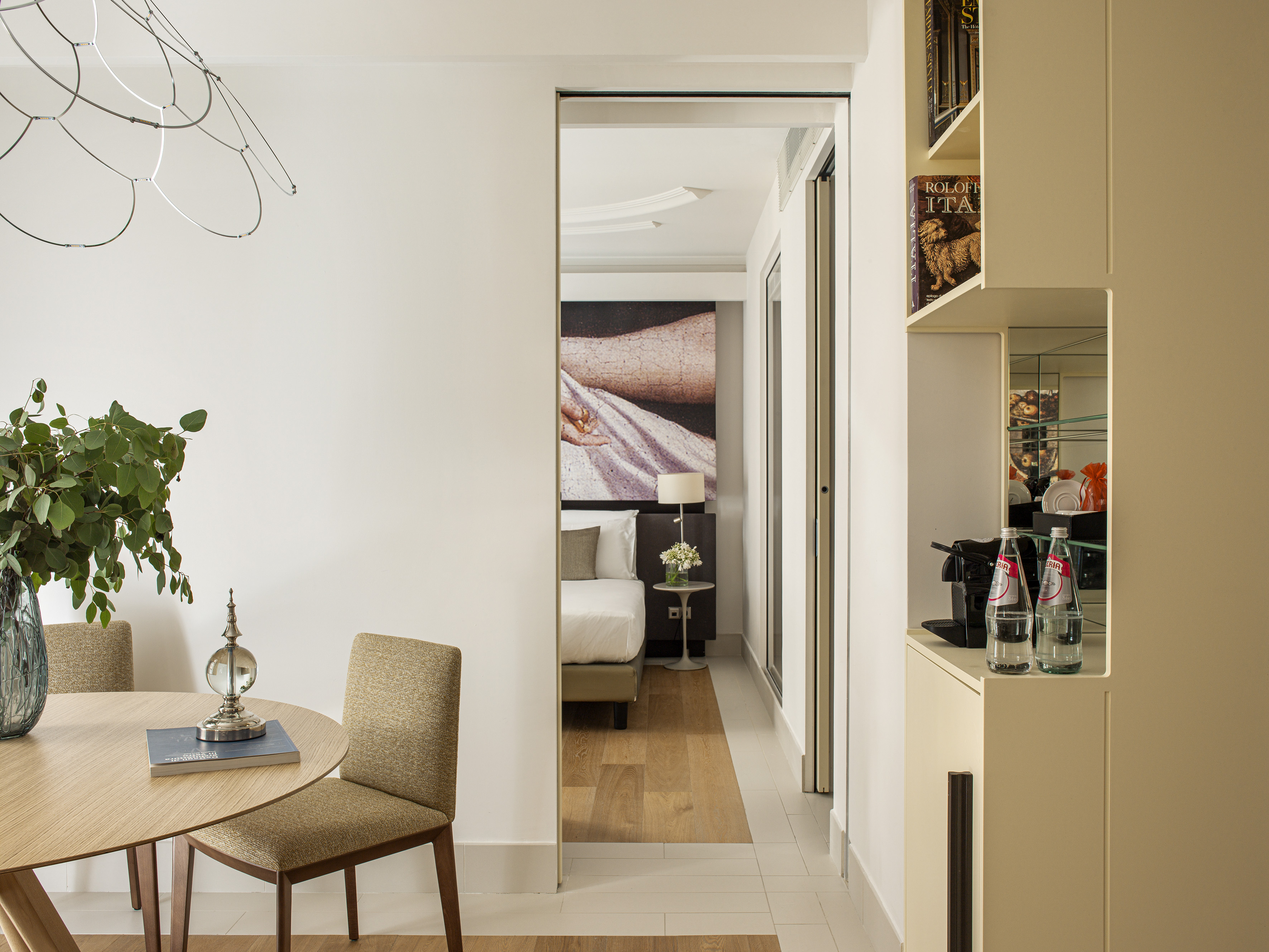 Modern hotel suite showing dining area, minibar, and bedroom.