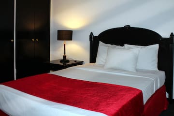 a bed with a red blanket and a lamp