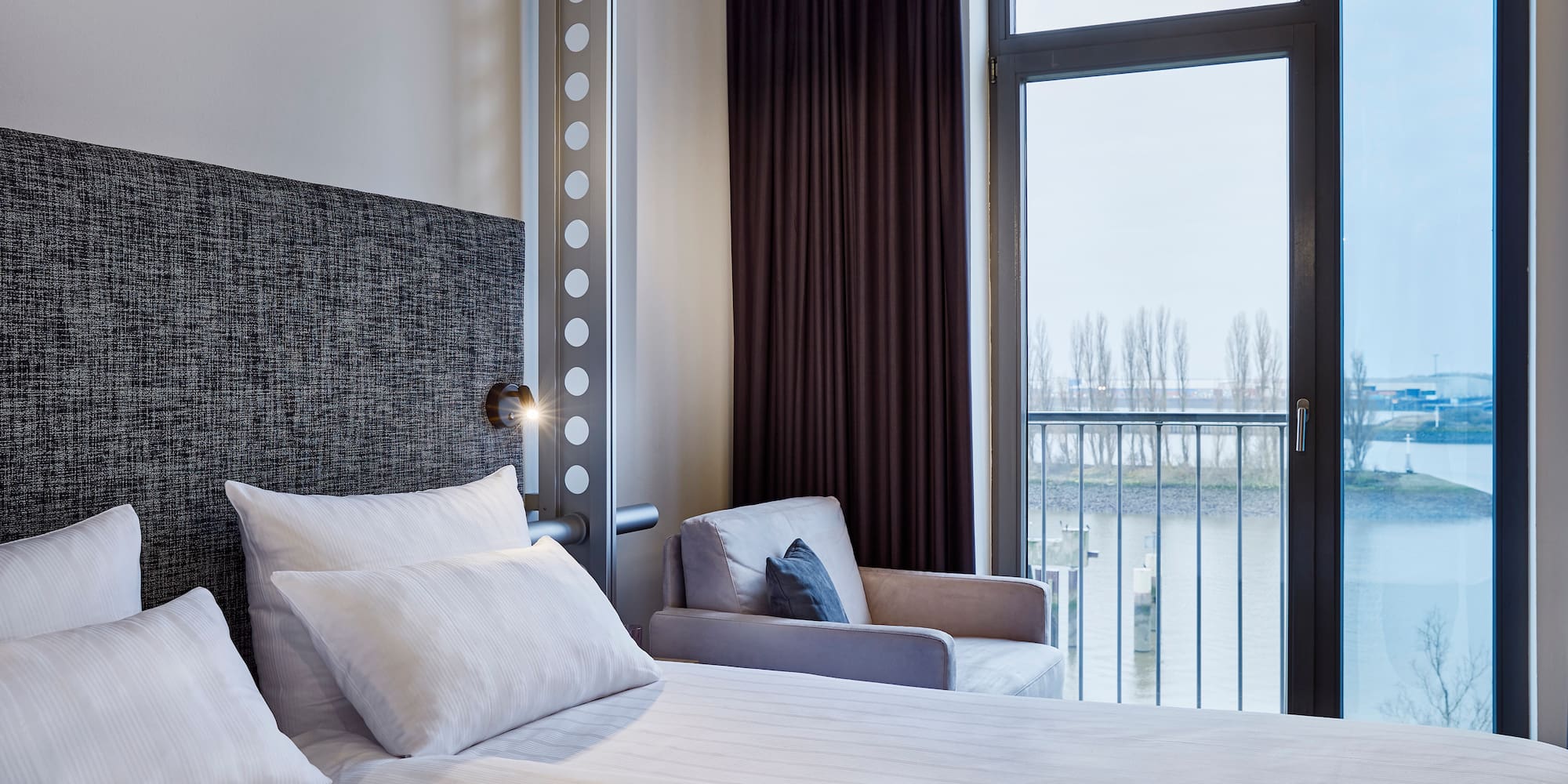 a bed with pillows and a chair in a room with a balcony