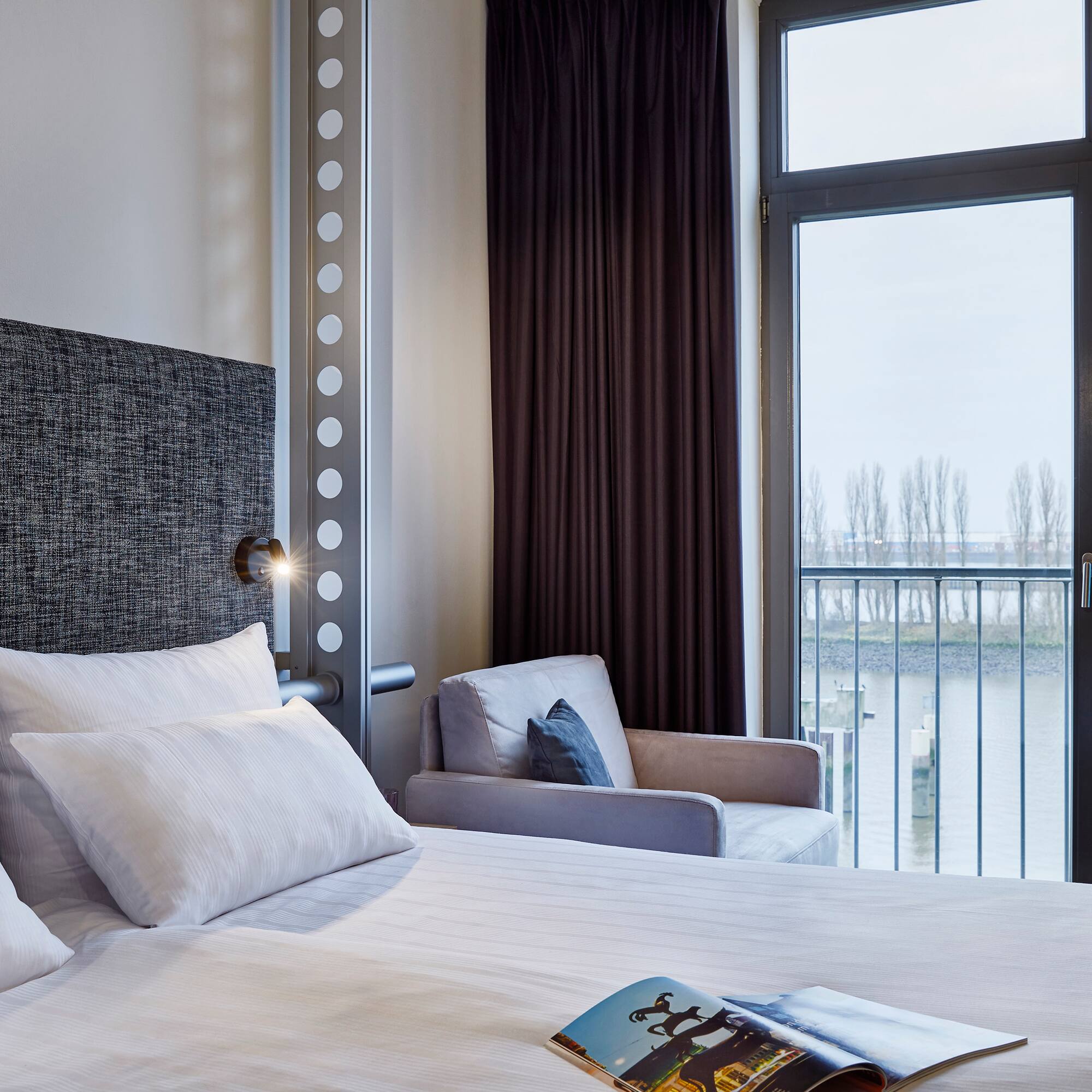 a bed with pillows and a chair in a room with a balcony