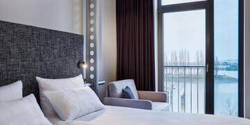 a bed with pillows and a chair in a room with a balcony