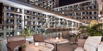 a patio with tables and chairs and a large building