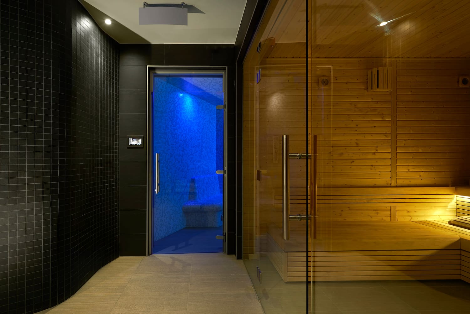 a sauna with a glass door and a wooden bench