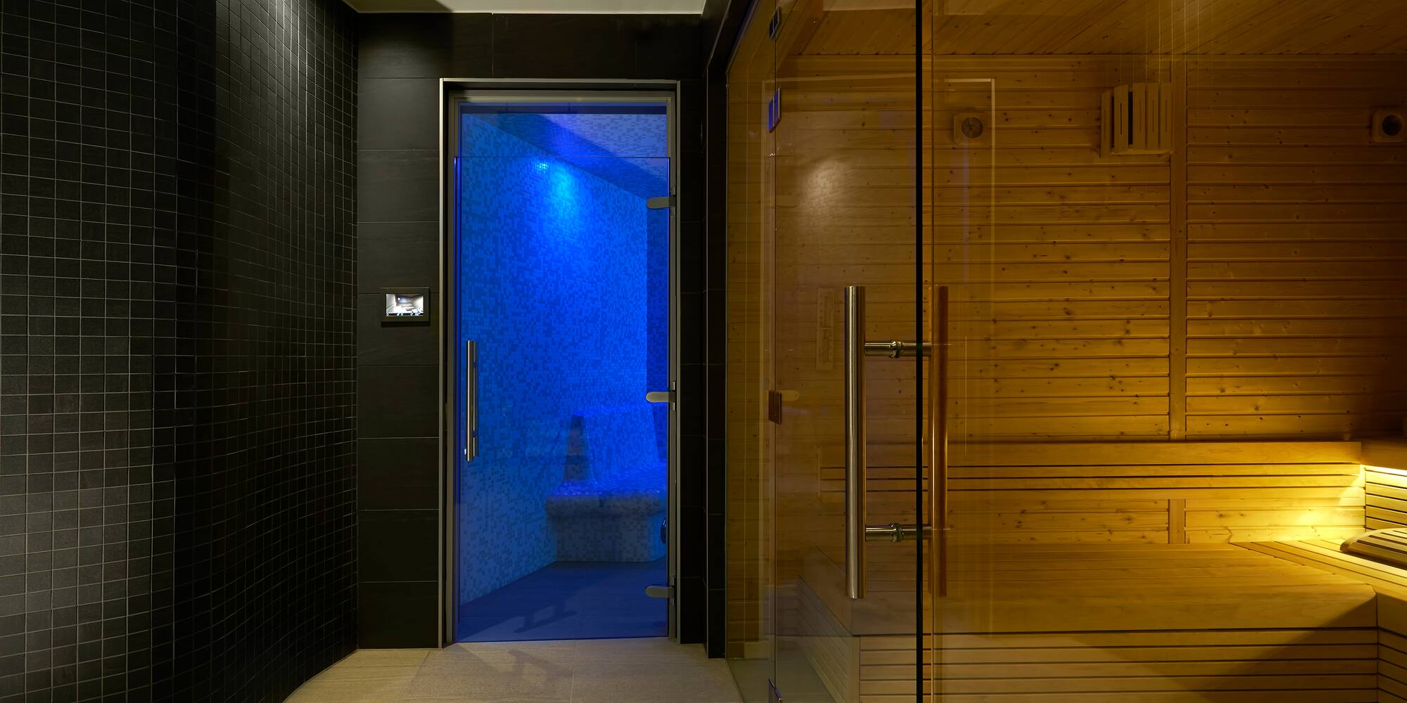 a sauna with a glass door and a wooden bench