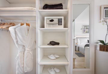 a white shelf with a white robe and a microwave and towels