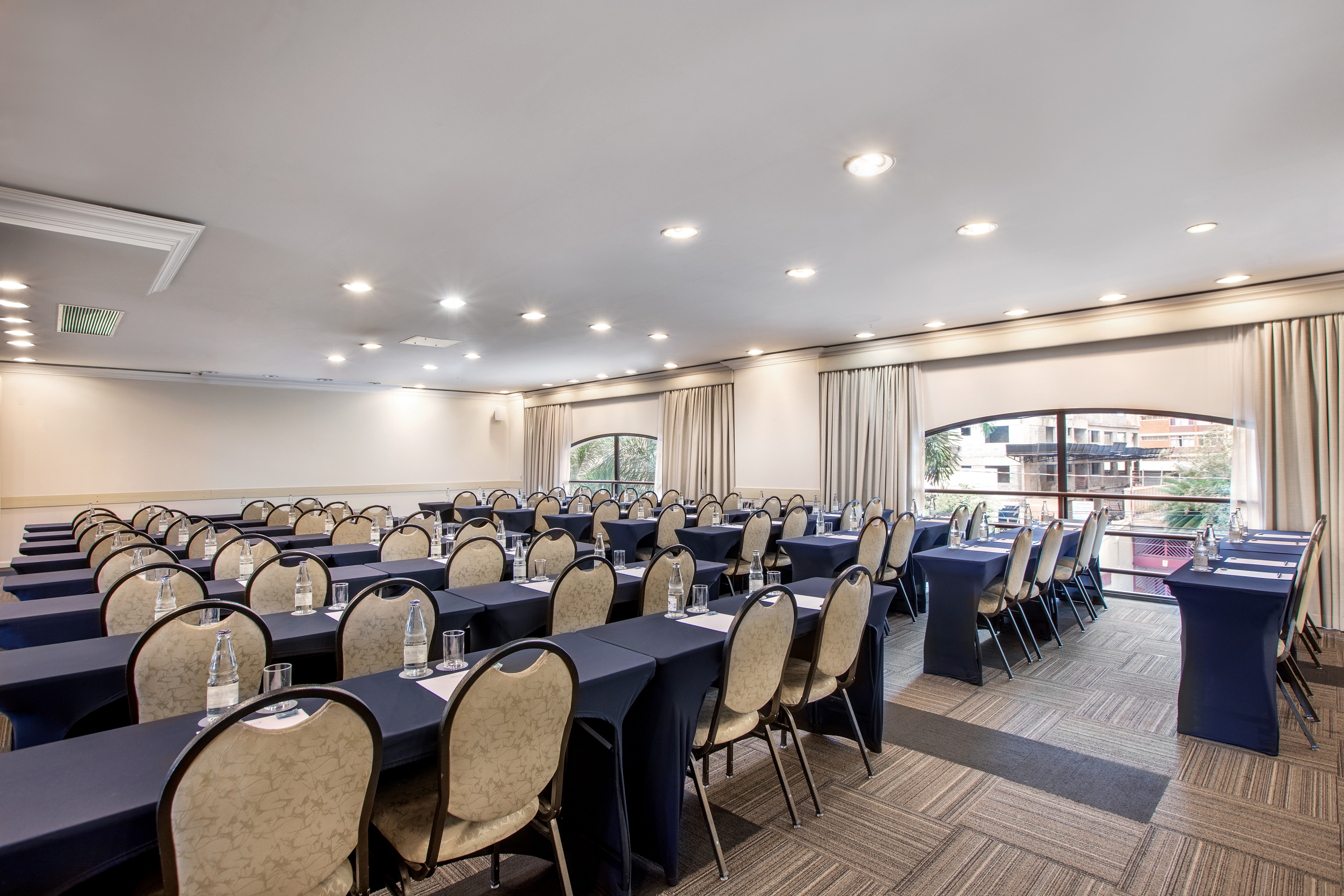 Spacious conference room ready for events, with dark blue tables and chairs.