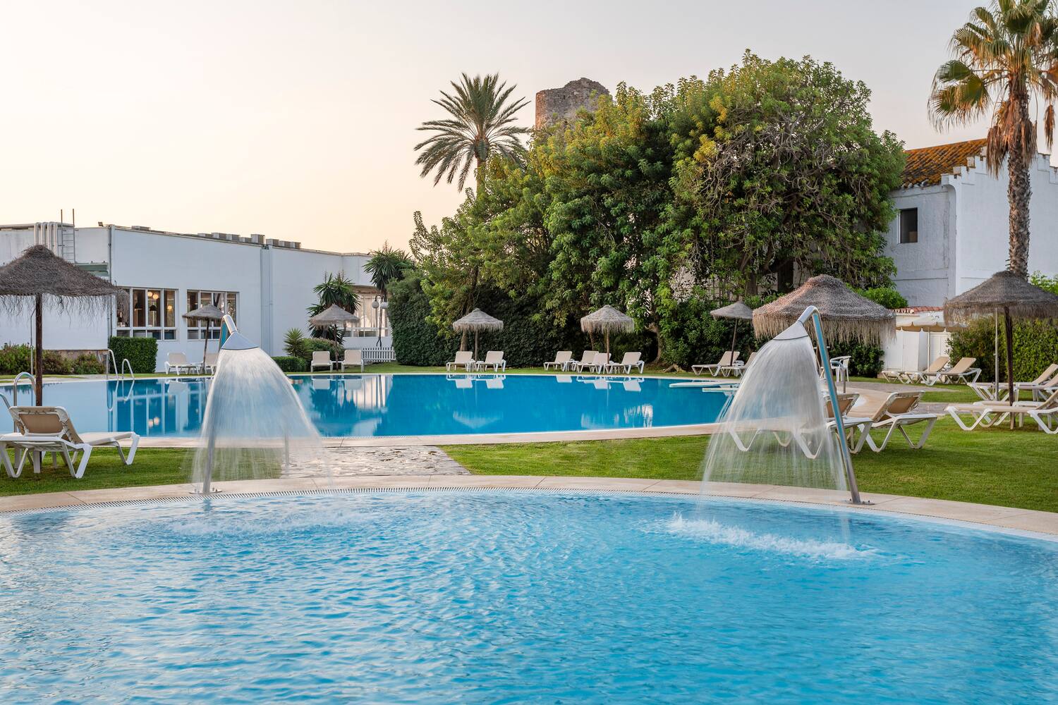 a pool with water jets and umbrellas