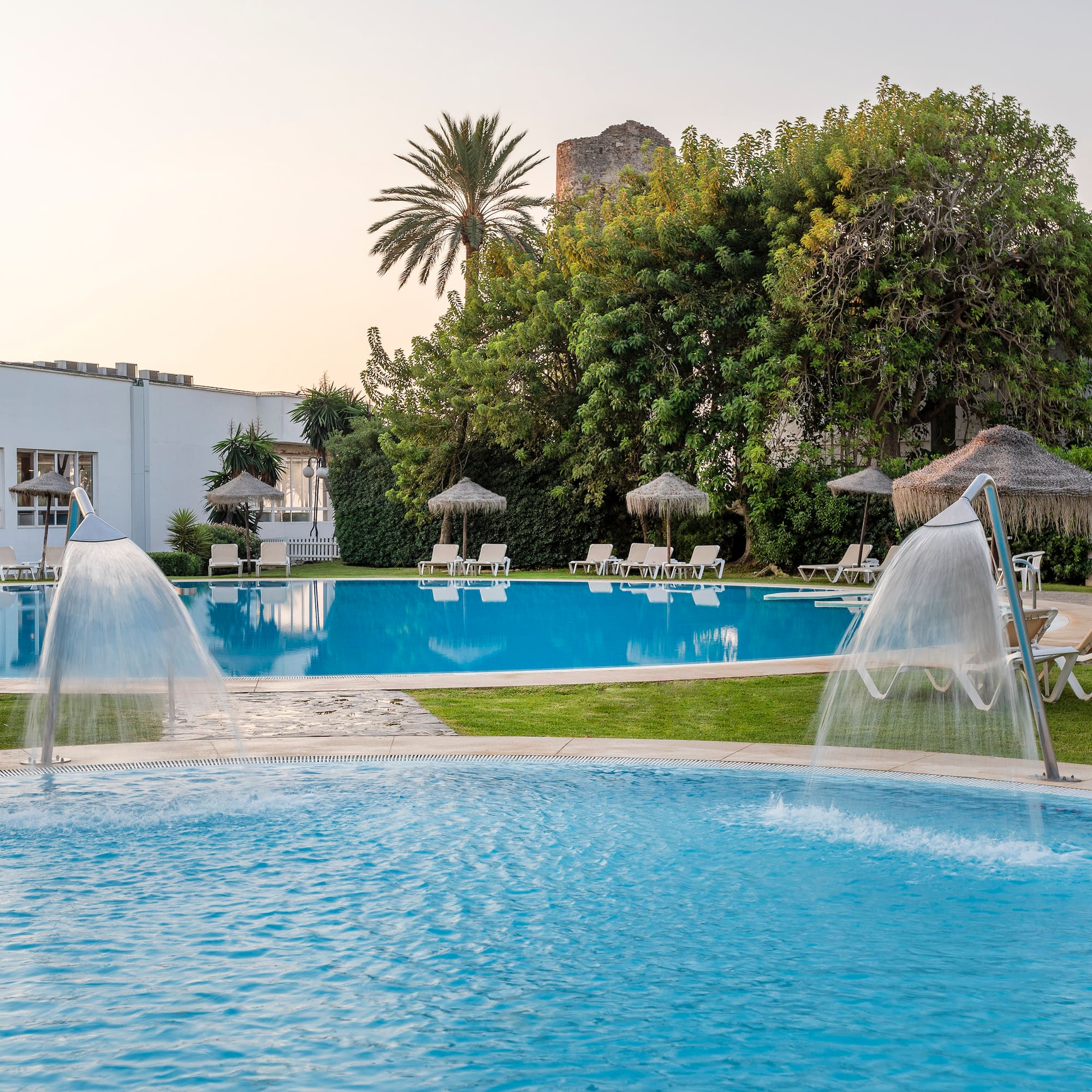 a pool with water jets and umbrellas