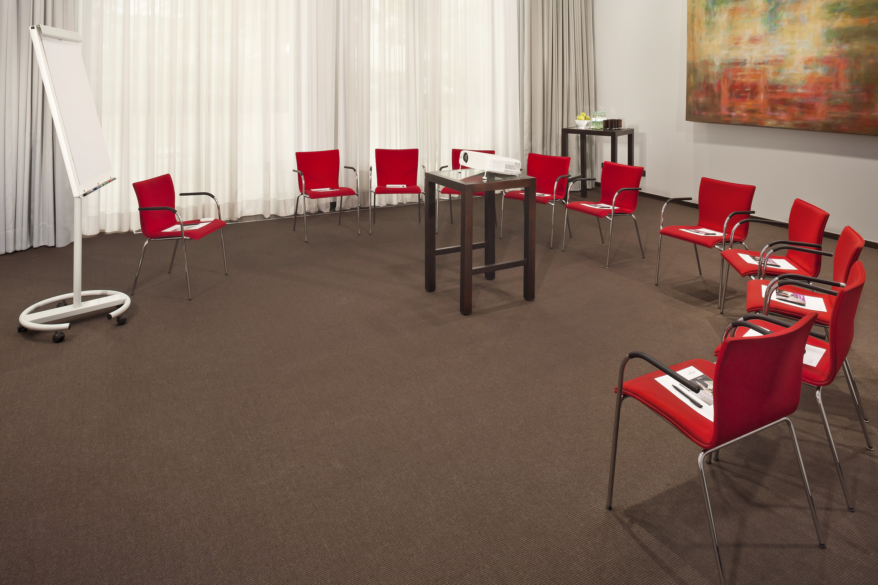 Meeting room with red chairs, projector, and flip chart for workshops.