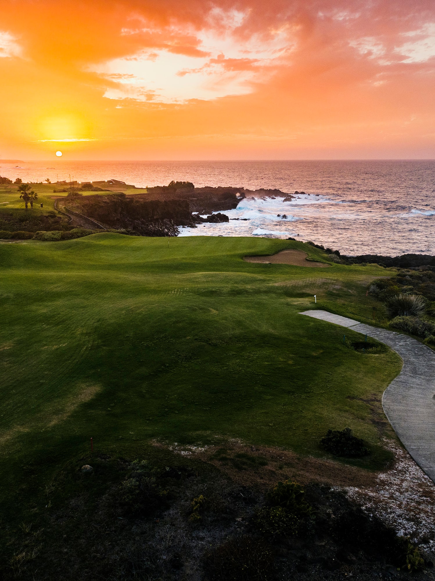 a golf course with a path and a body of water