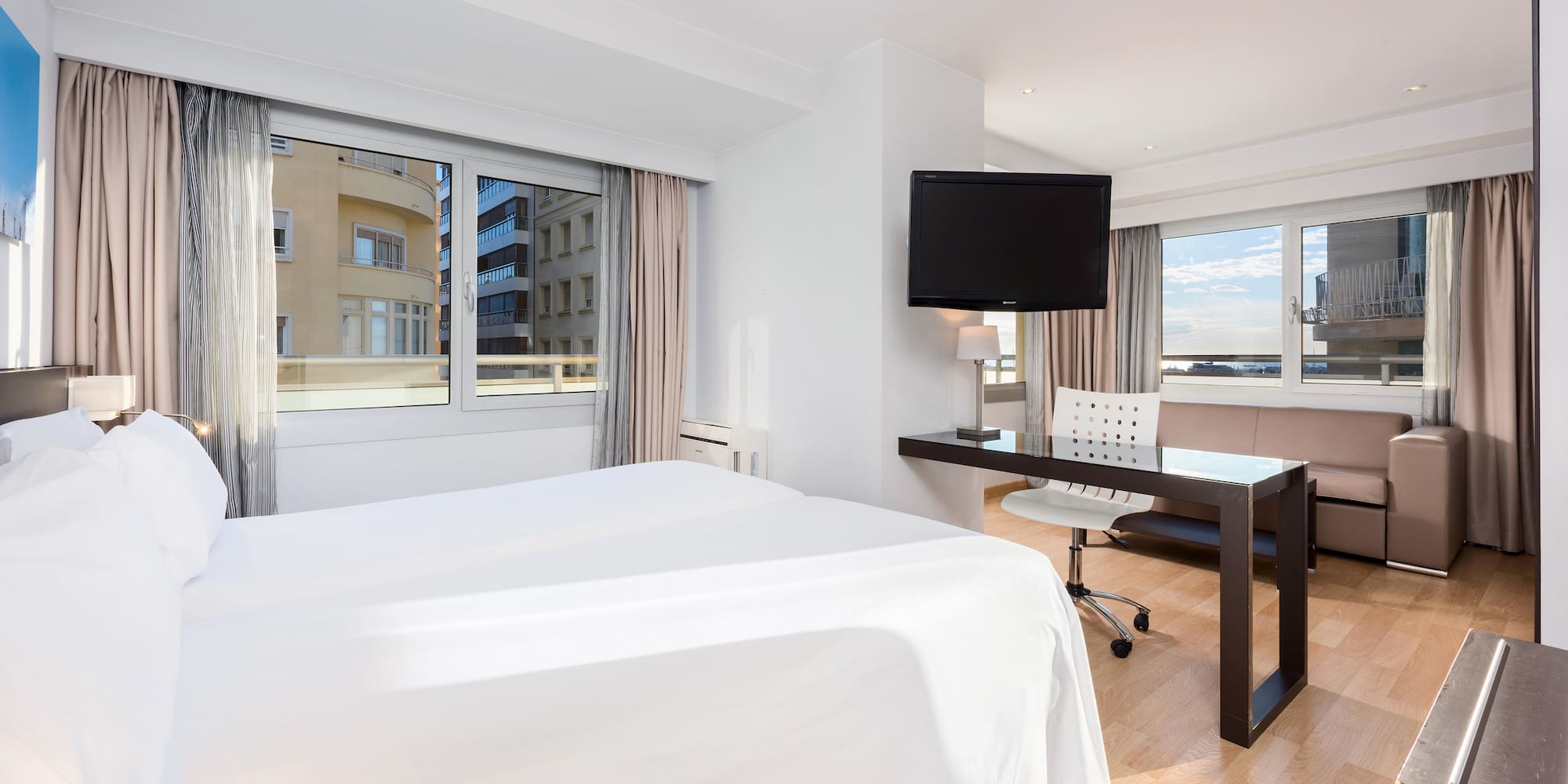 a room with a bed and a desk and a television