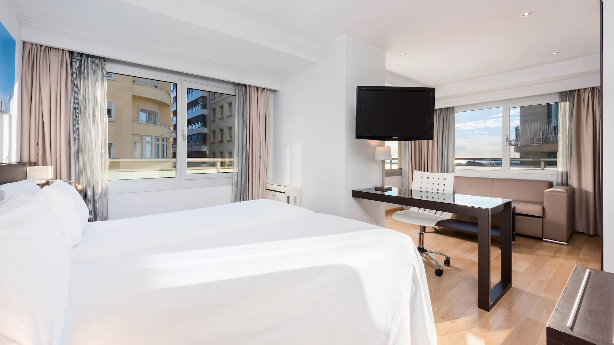 a room with a bed and a desk and a television