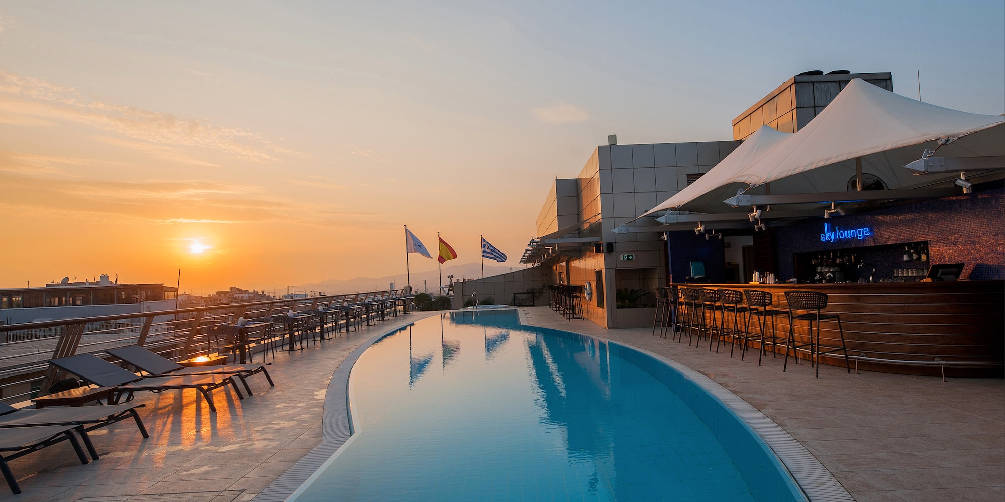 a pool with tables and chairs on a rooftop