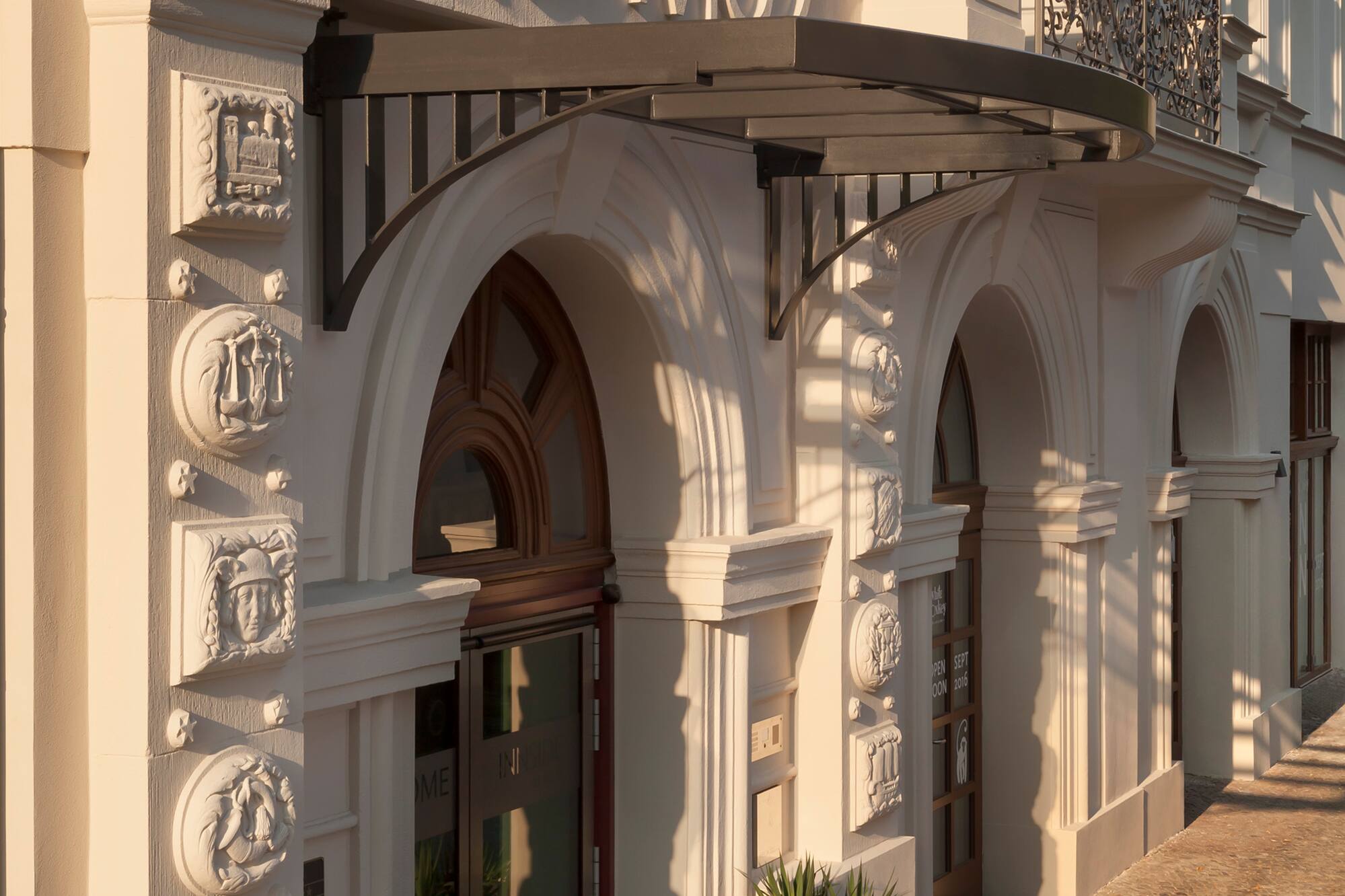 Kosmo hotel facade, classical architecture, Poseidon statue, arched entrance.