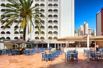 a patio with blue chairs and tables in front of a building