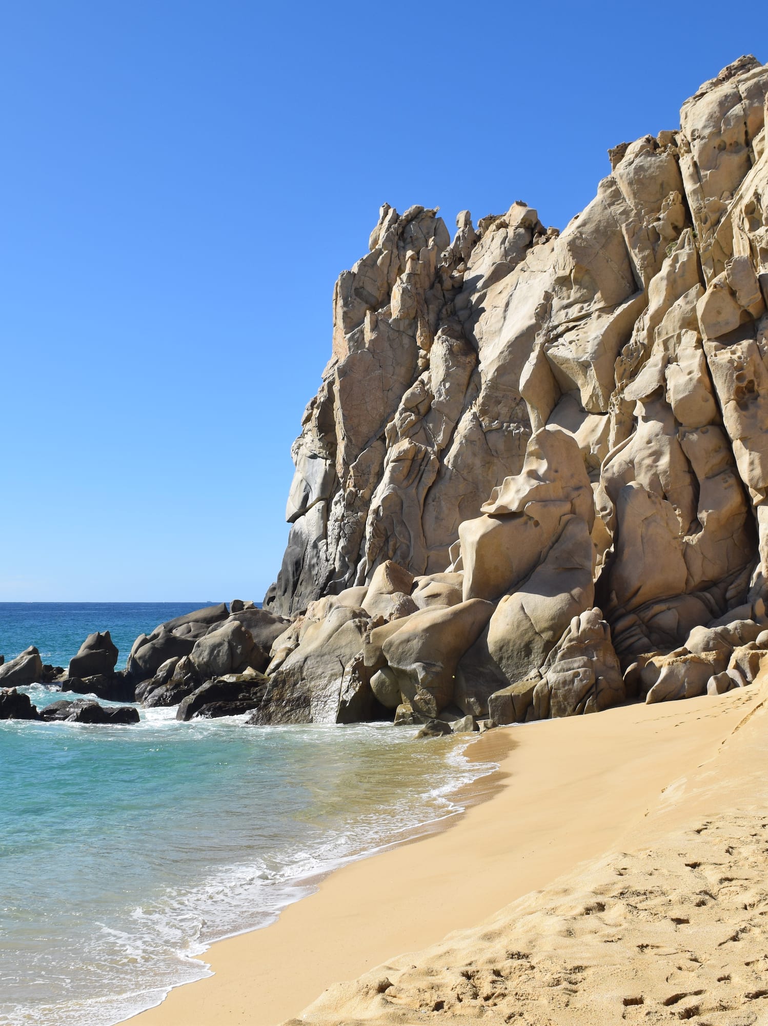 a sandy beach with rocks and water