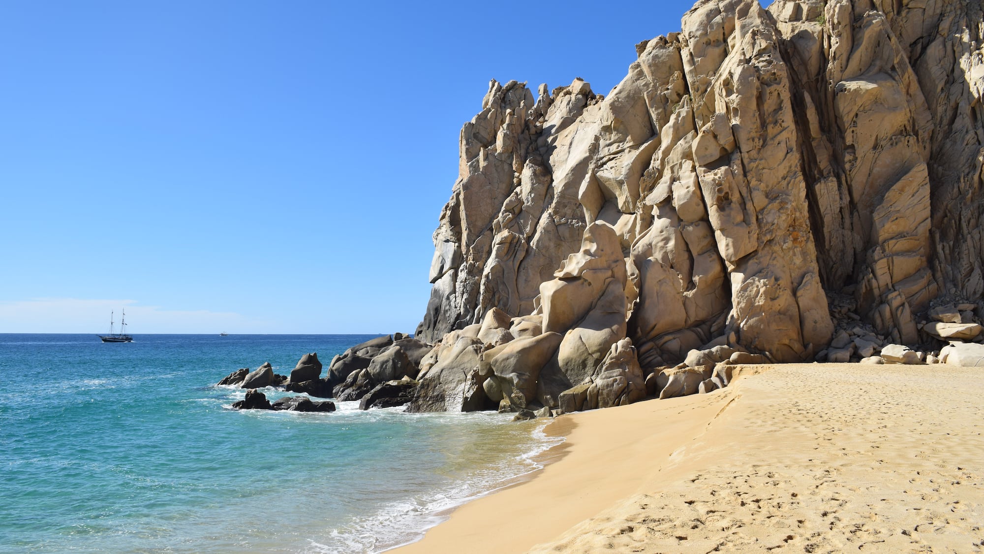 a sandy beach with rocks and water