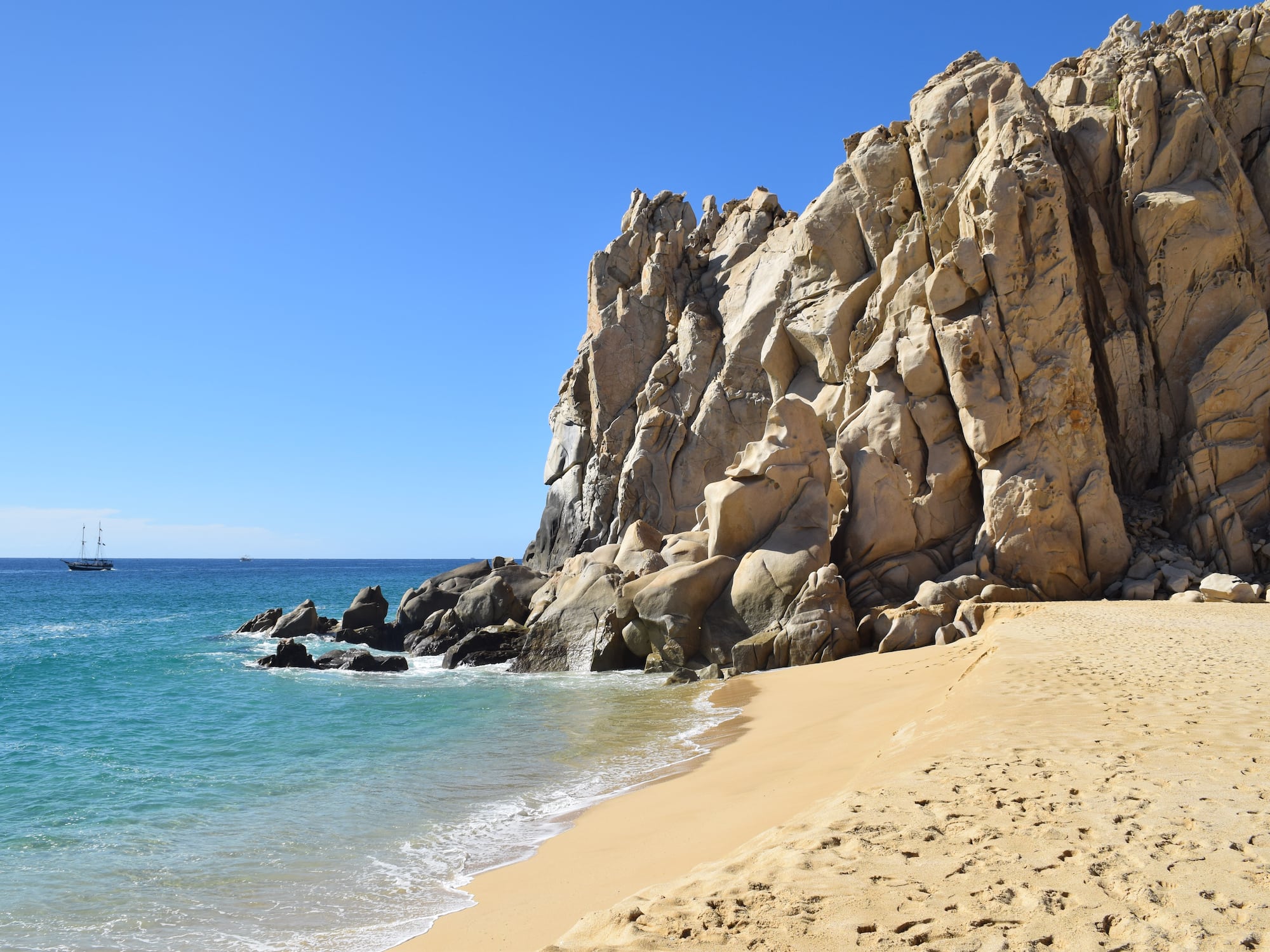 a sandy beach with rocks and water