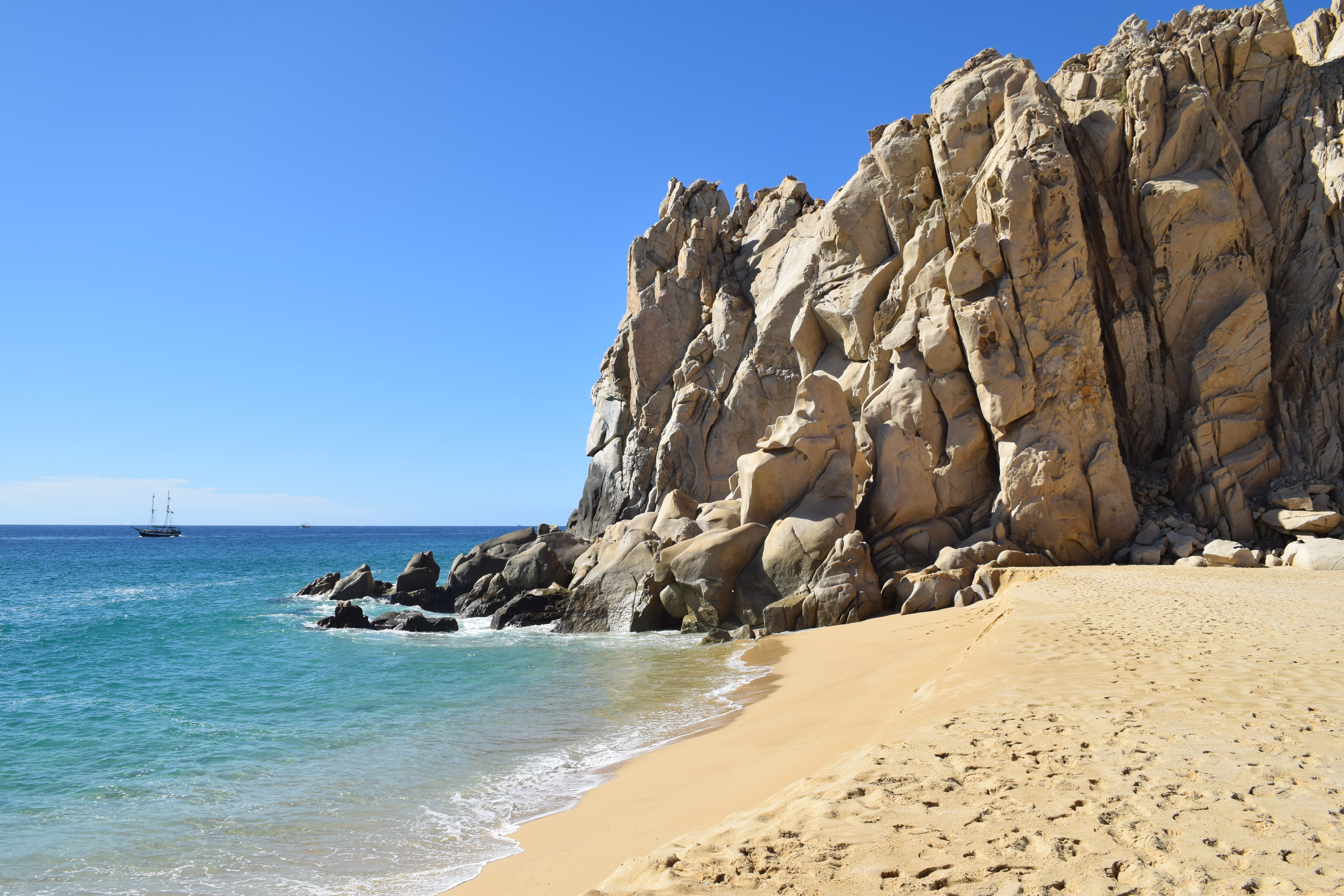 a sandy beach with rocks and water