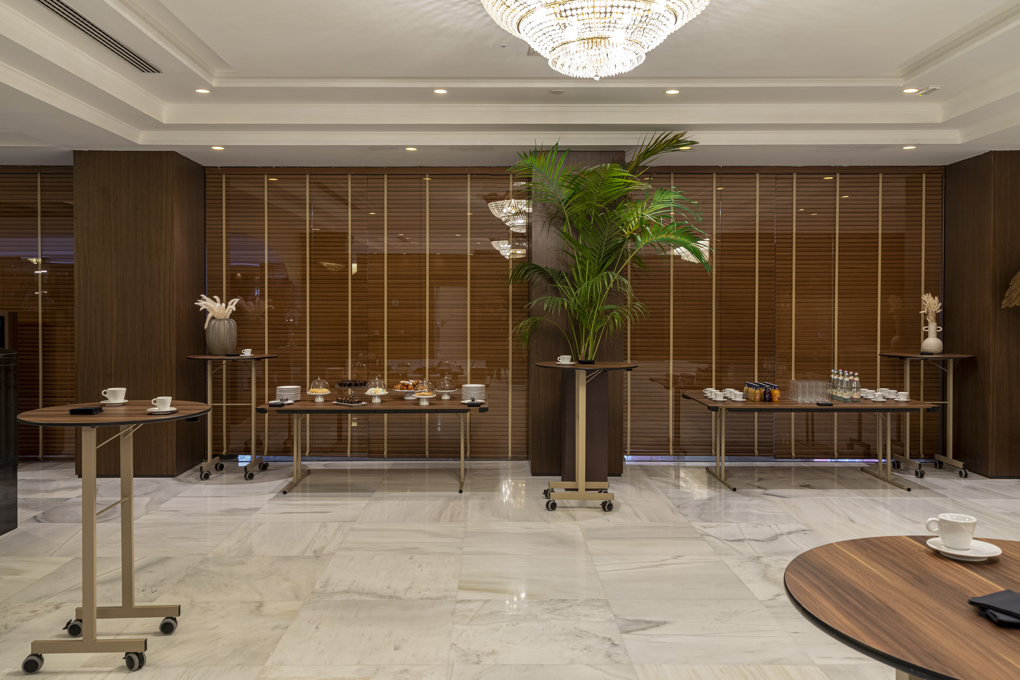 Luxury hotel coffee break setup with refreshments, snacks, and marble floor.