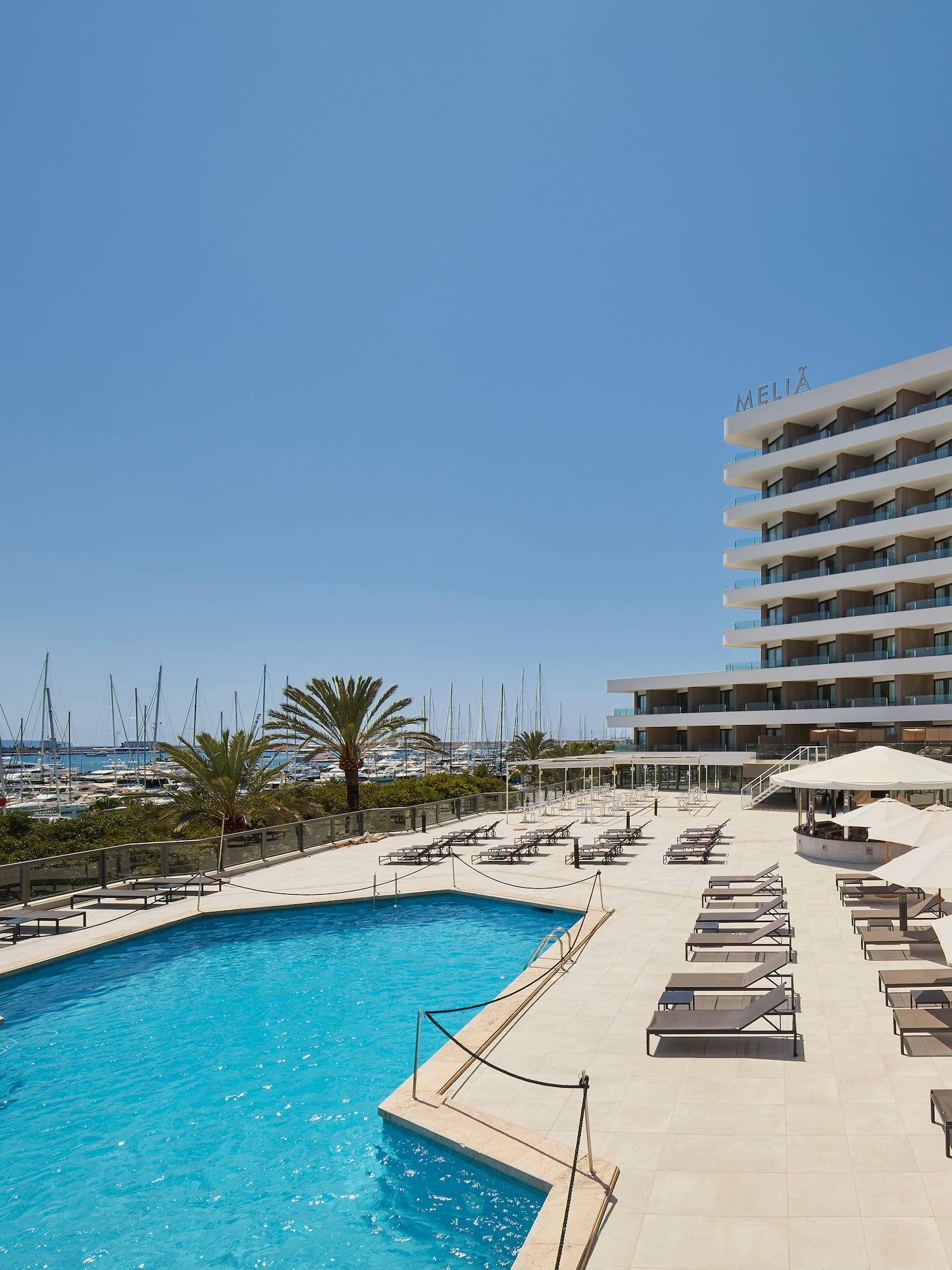 a pool with umbrellas and chairs by a building