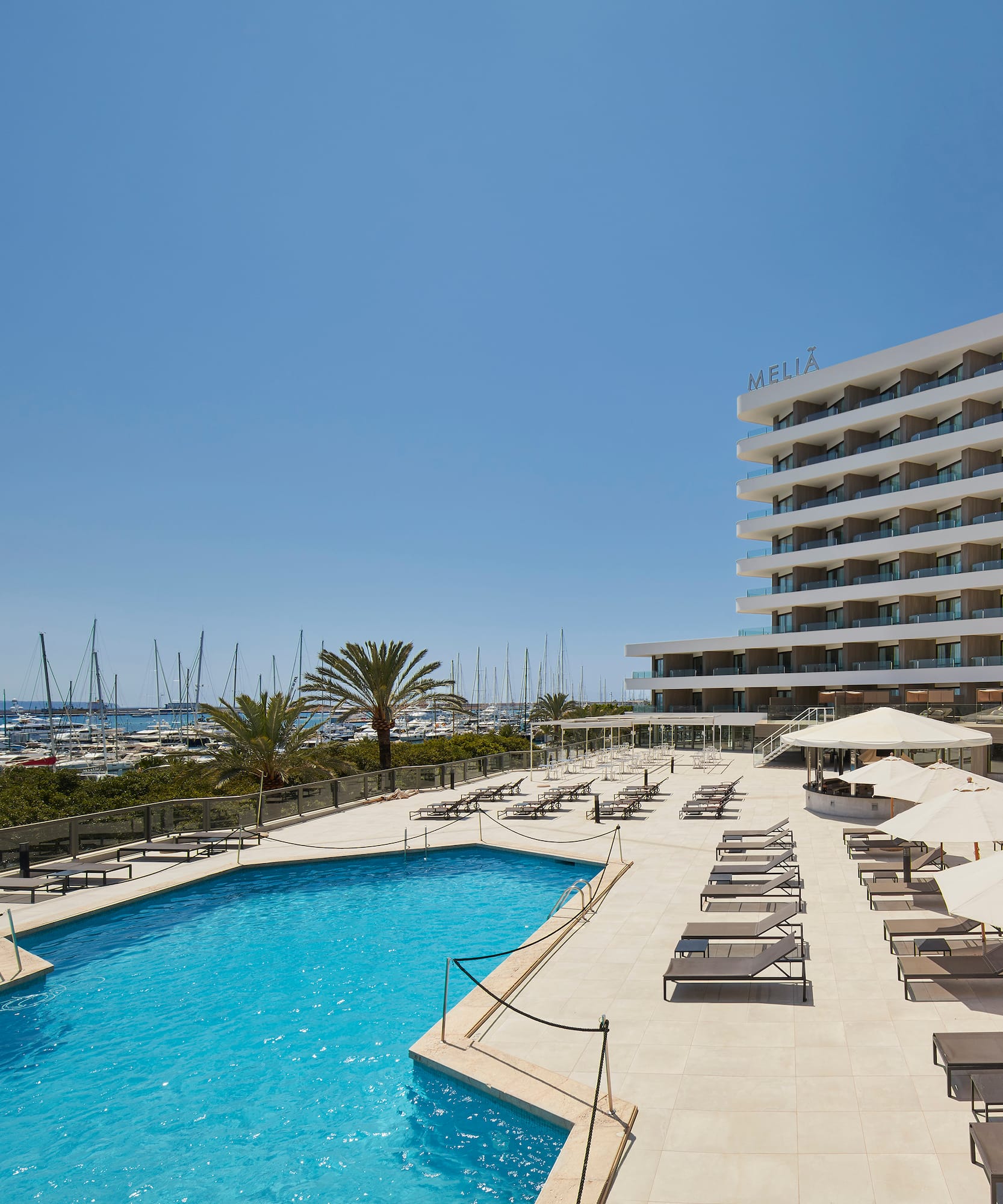 a pool with umbrellas and chairs by a building