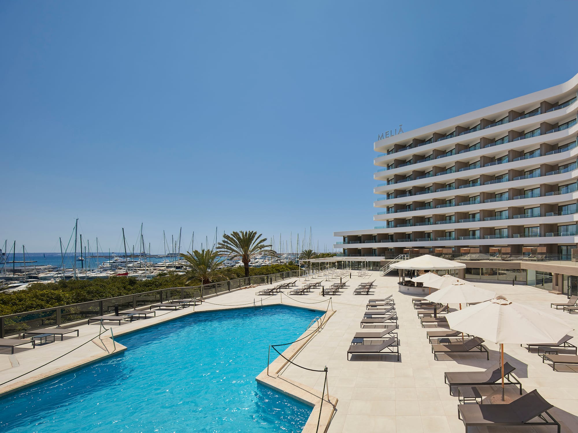 Meliá hotel pool deck with sun loungers overlooking a vibrant marina.