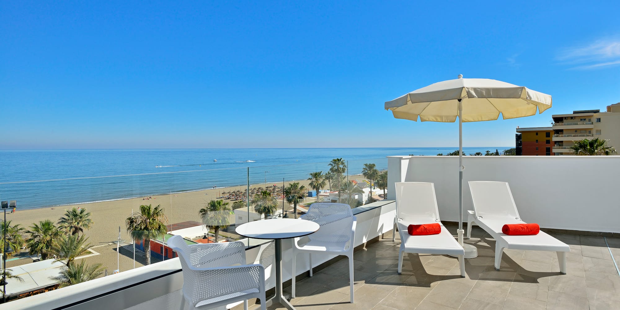 a white chairs and umbrella on a balcony overlooking a beach