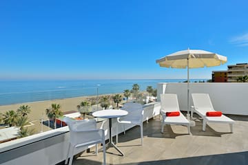a white chairs and umbrella on a balcony overlooking a beach
