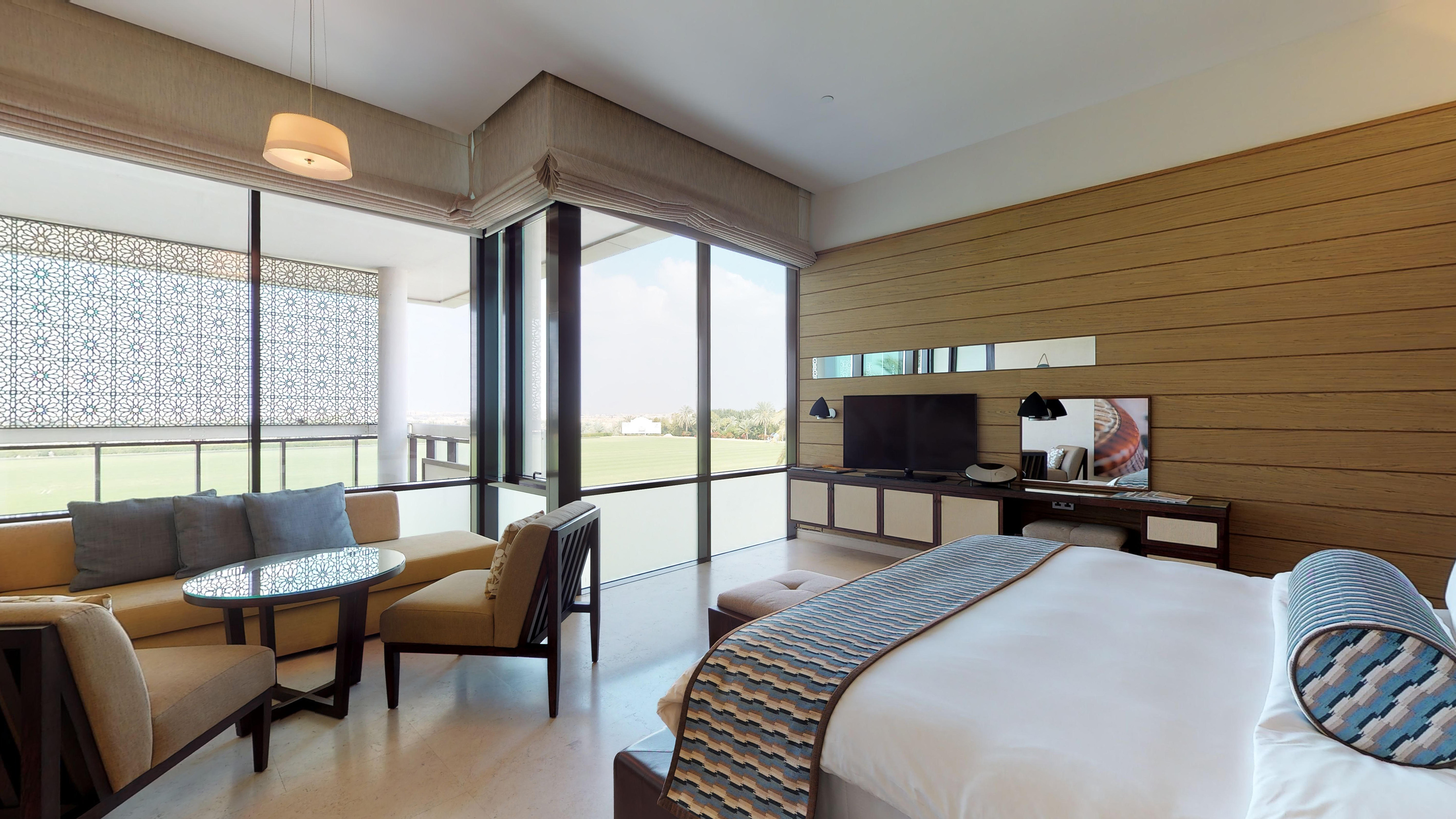 Luxury bedroom with large windows, green field view, and modern interior.