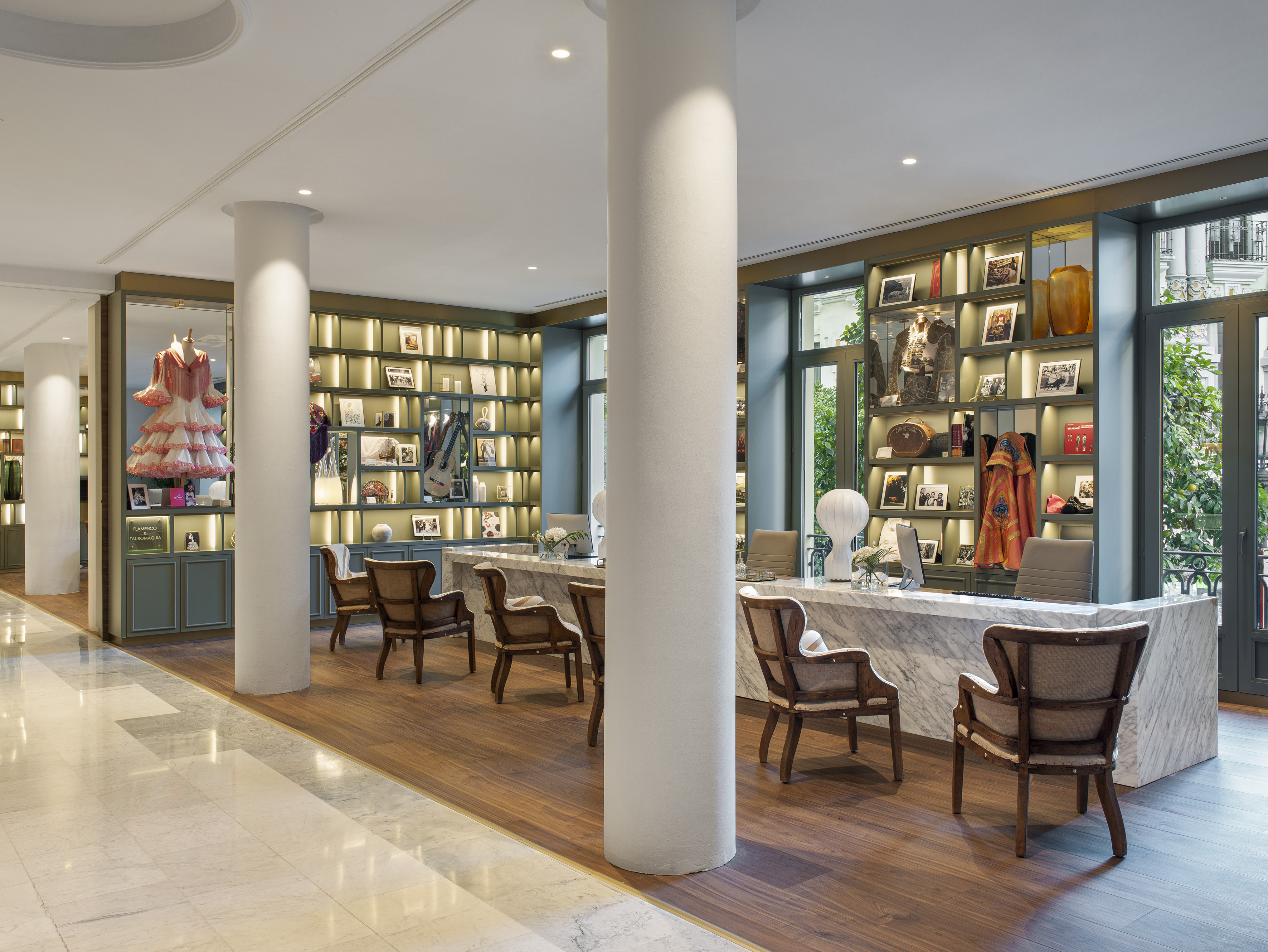 Hotel lobby with marble check-in desk, framed photos, and dark wood seating.