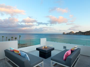 a patio with a fire pit overlooking the ocean