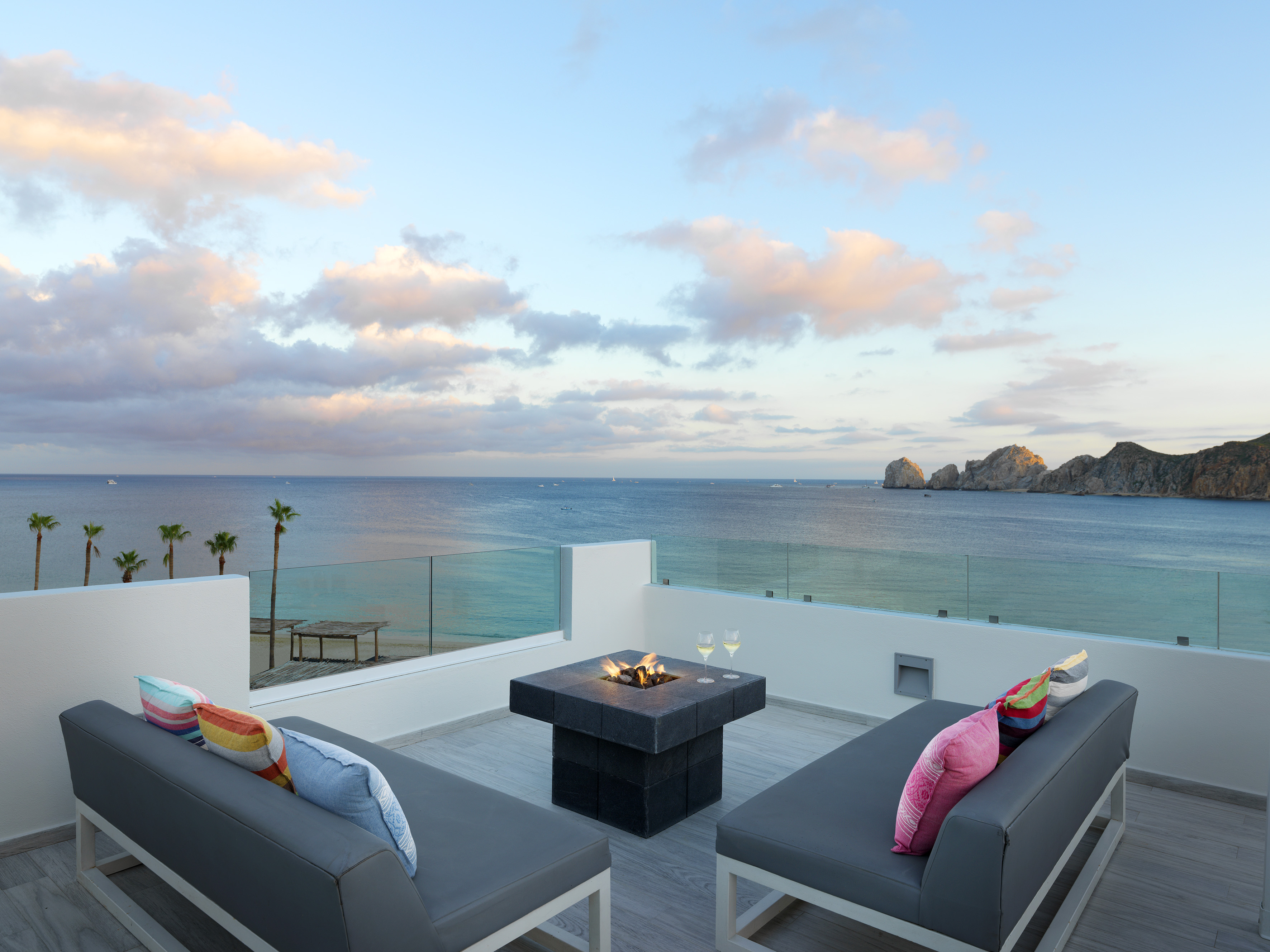a patio with a fire pit overlooking the ocean