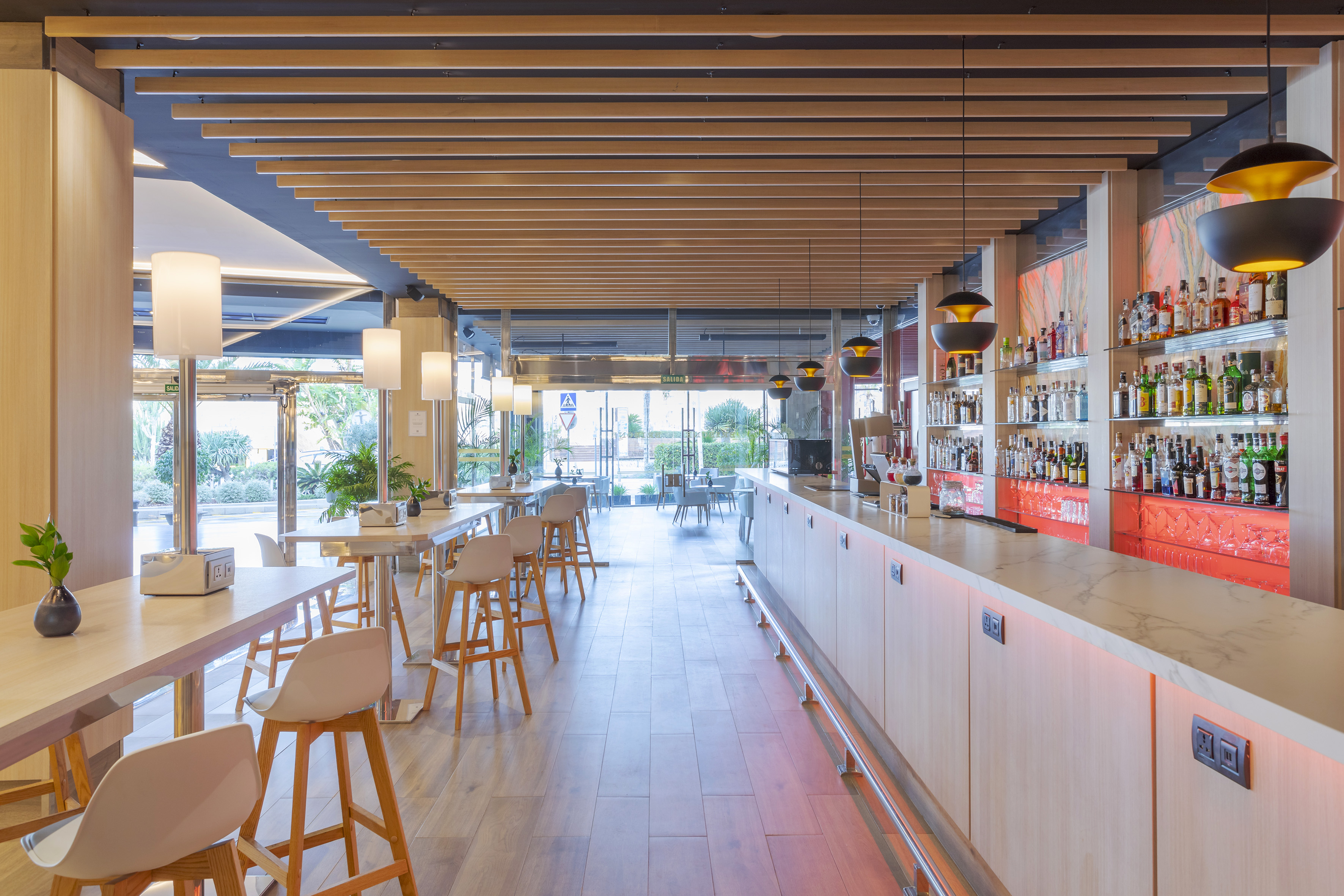 Modern hotel bar with wooden ceiling, stylish lighting, and full liquor display.
